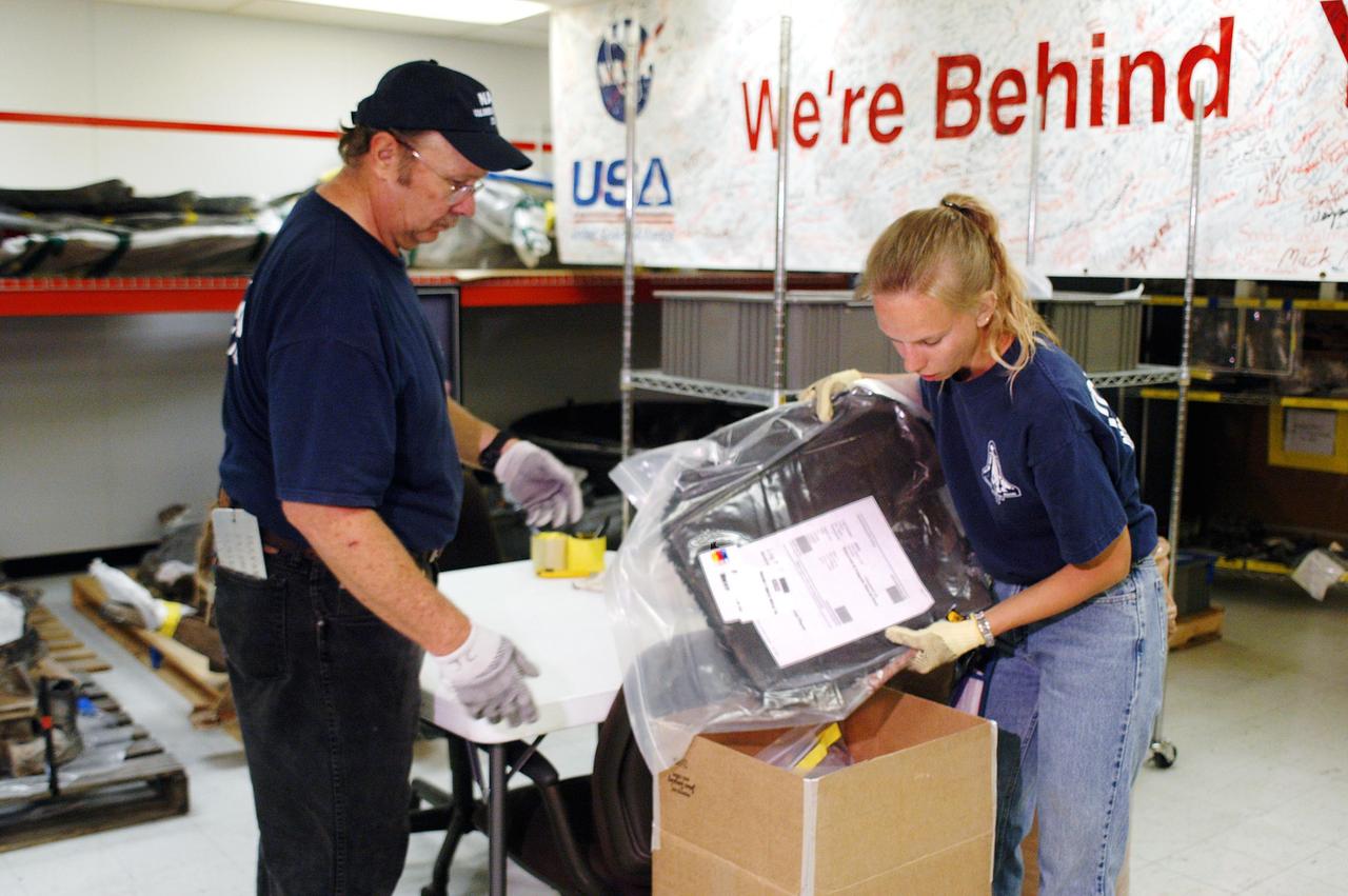 KENNEDY SPACE CENTER, FLA.  -  United Space Alliance workers J.C. Harrison (left) and Amy Mangiacapra (right) pack up pieces of Columbia debris for shipment to The Aerospace Corporation in El Segundo, Calif.   The pieces have been released for loan to the non-governmental agency for testing and research.   The Aerospace Corporation requested and will receive graphite/epoxy honeycomb skins from an Orbital Maneuvering System pod, Main Propulsion System Helium tanks, a Reaction Control System Helium tank and a Power Reactant Storage Distribution system tank. The company will use the parts to study re-entry effects on composite materials. NASA notified the Columbia crew’s families about the loan before releasing the items for study.  Researchers believe the testing will show how materials are expected to respond to various heating and loads' environments. The findings will help calibrate tools and models used to predict hazards to people and property from reentering hardware. The Aerospace Corporation will have the debris for one year to perform analyses to estimate maximum temperatures during reentry based upon the geometry and mass of the recovered composite.  Columbia’s debris is stored in the VAB.