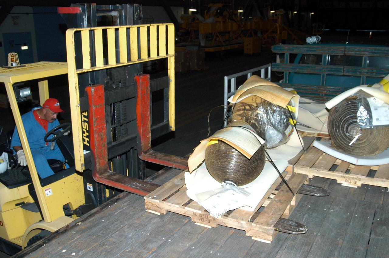 KENNEDY SPACE CENTER, FLA.  -  After being wrapped and secured on pallets, pieces of Columbia debris are loaded onto a truck to transport them to the shipping facility for travel to The Aerospace Corporation in El Segundo, Calif.  The pieces have been released for loan to the non-governmental agency for testing and research.  The Aerospace Corporation requested and will receive graphite/epoxy honeycomb skins from an Orbital Maneuvering System pod, Main Propulsion System Helium tanks, a Reaction Control System Helium tank and a Power Reactant Storage Distribution system tank. The company will use the parts to study re-entry effects on composite materials. NASA notified the Columbia crew’s families about the loan before releasing the items for study.  Researchers believe the testing will show how materials are expected to respond to various heating and loads' environments. The findings will help calibrate tools and models used to predict hazards to people and property from reentering hardware. The Aerospace Corporation will have the debris for one year to perform analyses to estimate maximum temperatures during reentry based upon the geometry and mass of the recovered composite.  Columbia’s debris is stored in the VAB.