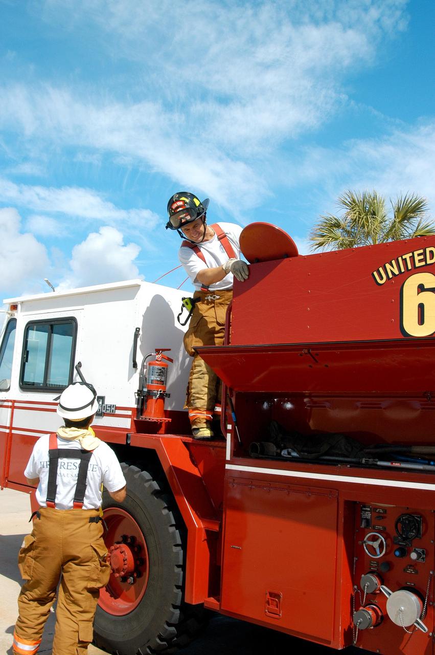 KENNEDY SPACE CENTER, FLA.  -  At Cape Canaveral Air Force Station, Lt. Keith Abell (left) and KSC Firefighter Chris Maupin store equipment on the fire truck.  They and other KSC firefighters teamed up with task forces from Satellite Beach, Malabar, Melbourne, Palm Bay, Patrick Air Force Base and Brevard County to help fight wildfires in the Palm Bay and Malabar areas that threatened homes and property during the Memorial Day holiday weekend.