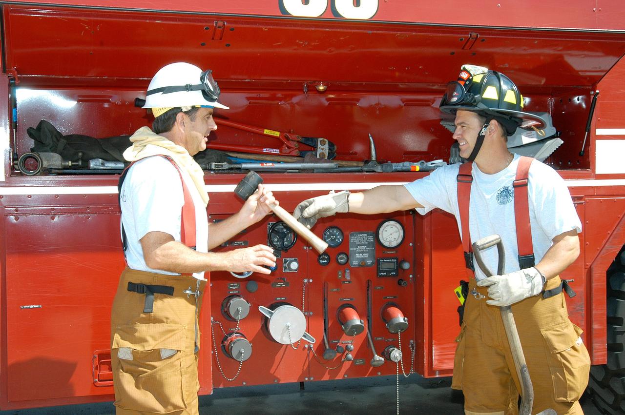 KENNEDY SPACE CENTER, FLA.  -  At Cape Canaveral Air Force Station, Lt. Keith Abell (left) hands equipment to KSC Firefighter Chris Maupin for storage.  They and other KSC firefighters teamed up with task forces from Satellite Beach, Malabar, Melbourne, Palm Bay, Patrick Air Force Base and Brevard County to help fight wildfires in the Palm Bay and Malabar areas that threatened homes and property during the Memorial Day holiday weekend.