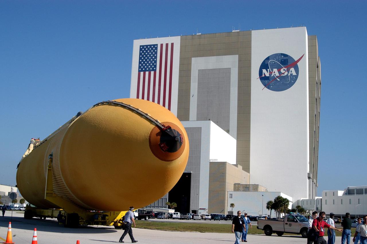 KENNEDY SPACE CENTER, FLA. - With employees walking alongside, the external tank atop its transporter turns the corner from the Vehicle Assembly Building toward the Turn Basin and the Banana River. The tank will be loaded onto the waiting barge and transferred to the Michoud Space Systems Assembly Facility near New Orleans where redesign of the external tank is underway for Return to Flight.