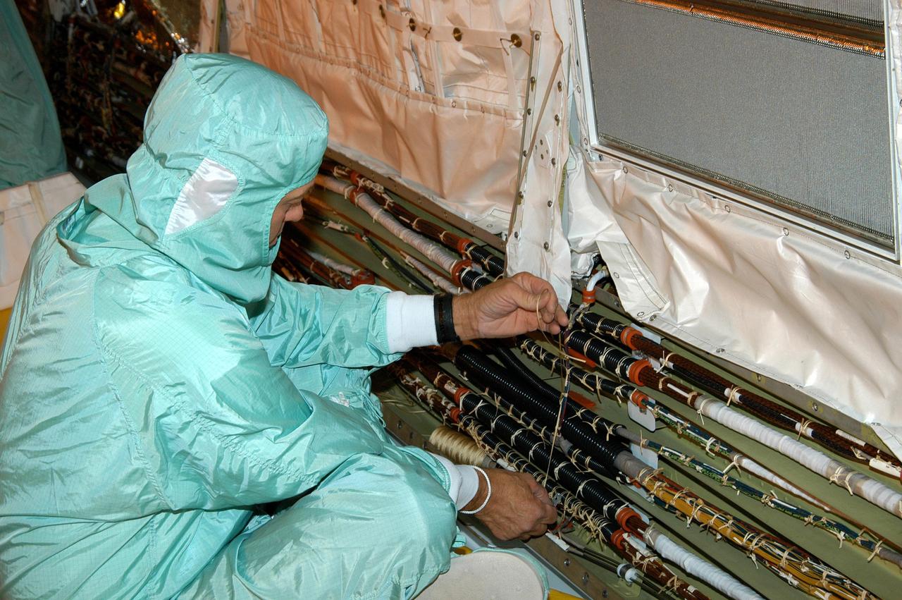 KENNEDY SPACE CENTER, FLA.  - In the Orbiter Processing Facility, a worker is installing wiring in Discovery’s cargo bay that will support the addition of an Orbiter Boom Sensor System (OBSS) .  The OBSS is one of the new safety measures for Return to Flight, equipping the Shuttle with cameras and laser systems to inspect the Shuttle’s Thermal Protection System while in space.  Discovery is designated as the Return to Flight vehicle for mission STS-114, no earlier than March 2005.