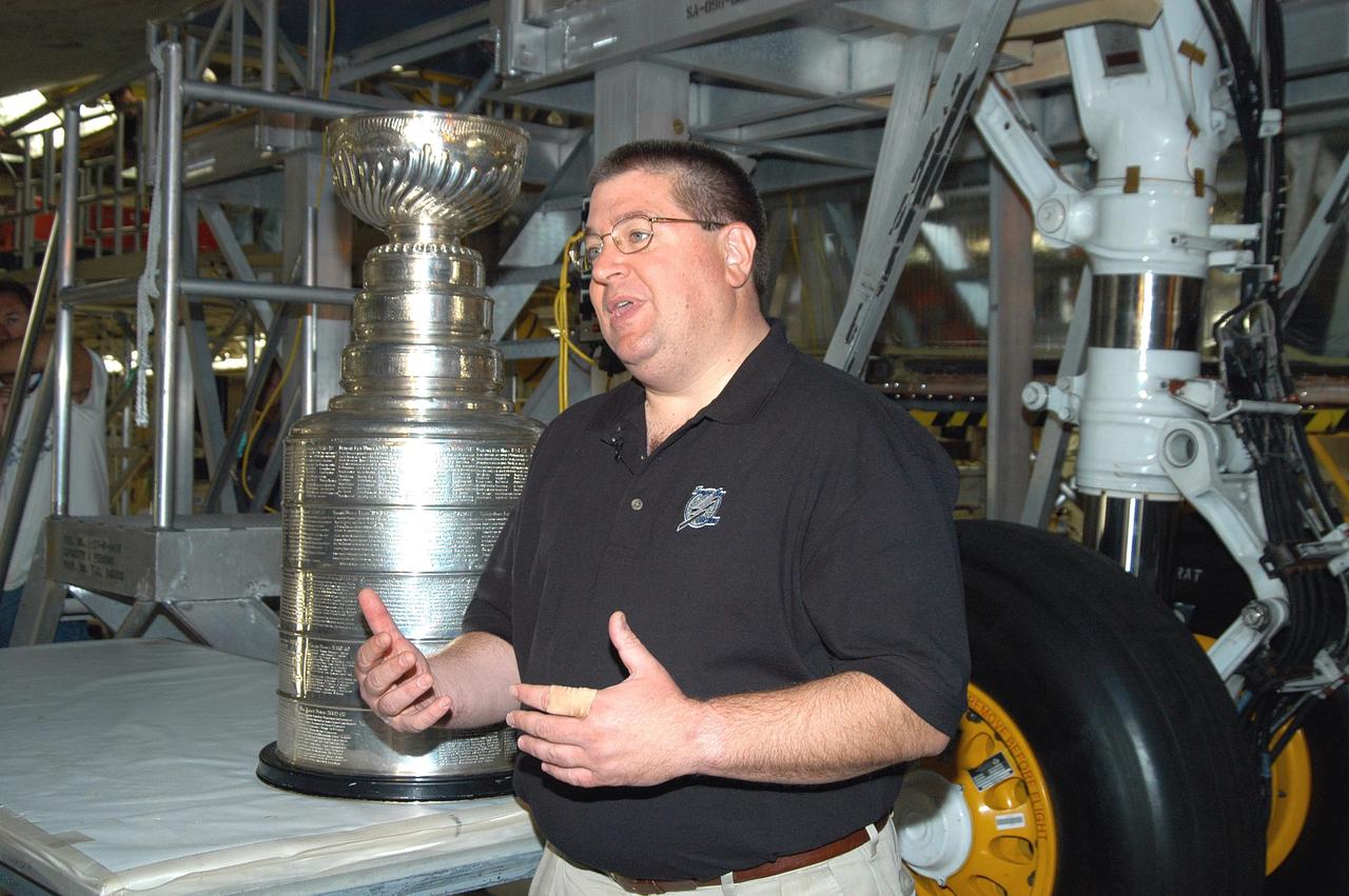 KENNEDY SPACE CENTER, FLA. - Jay Feaster, general manager of the National Hockey League 2004 Champions Tampa Bay Lightning, stands next to the Stanley Cup, which he brought to KSC while on a tour. The cup stands next to the orbiter Discovery in the Orbiter Processing Facility. The cup was also briefly available for viewing by employees in the KSC Training Auditorium. The Stanley Cup weighs 35 pounds and is more than 100 years old. The Lightning will be added to the cup in September.