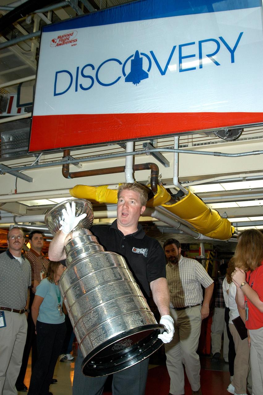 KENNEDY SPACE CENTER, FLA. - In the Orbiter Processing Facility, Mike Bolt holds the Stanley Cup, won this year by the National Hockey League’s Tampa Bay Lightning. Bolt is the Stanley Cup keeper. The cup was also briefly available for viewing by employees in the KSC Training Auditorium. Jay Feaster, general manager of the Tampa Bay Lightning, brought the cup to KSC while on a tour. The Stanley Cup weighs 35 pounds and is more than 100 years old. The Lightning will be added to the cup in September.