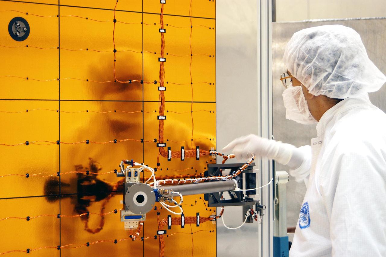 KENNEDY SPACE CENTER, FLA. - At Astrotech Space Operations in Titusville, Fla., a worker checks wiring on the Mercury Surface, Space Environment, Geochemistry and Ranging (MESSENGER) spacecraft. Two solar arrays will be installed June 24-25, followed by a deployment testLaunch is scheduled for July 30, 2004 from Pad 17-B at Cape Canaveral Air Force Station. The spacecraft will fly past Earth once, Venus twice and Mercury three times before starting a year-long orbital study of Mercury in March 2011. MESSENGER was built for NASA by the Johns Hopkins University Applied Physics Laboratory in Laurel, Md.