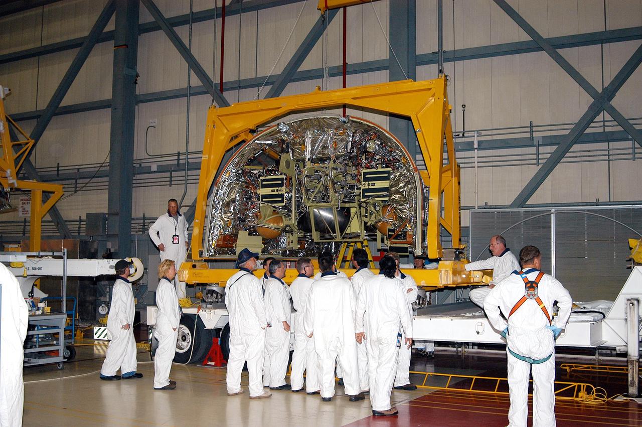 KENNEDY SPACE CENTER, FLA. - Workers in the Orbiter Processing Facility stand by as a crane lifts the Forward Reaction Control System (FRCS) for installation in Discovery. Located in the forward fuselage nose area, the FRCS provides the thrust for attitude (rotational) maneuvers (pitch, yaw and roll) and for small velocity changes along the orbiter axis (translation maneuvers). Discovery is designated as the Return to Flight vehicle for mission STS-114, no earlier than March 2005.