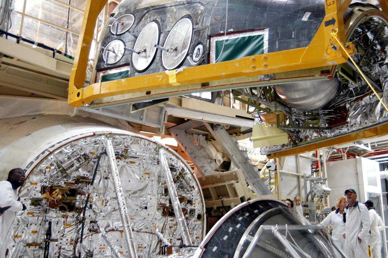 KENNEDY SPACE CENTER, FLA. - In the Orbiter Processing Facility, the Forward Reaction Control System (FRCS) is lowered toward Discovery’s forward fuselage nose area where it will be installed. The FRCS provides the thrust for attitude (rotational) maneuvers (pitch, yaw and roll) and for small velocity changes along the orbiter axis (translation maneuvers). Discovery is designated as the Return to Flight vehicle for mission STS-114, no earlier than March 2005.