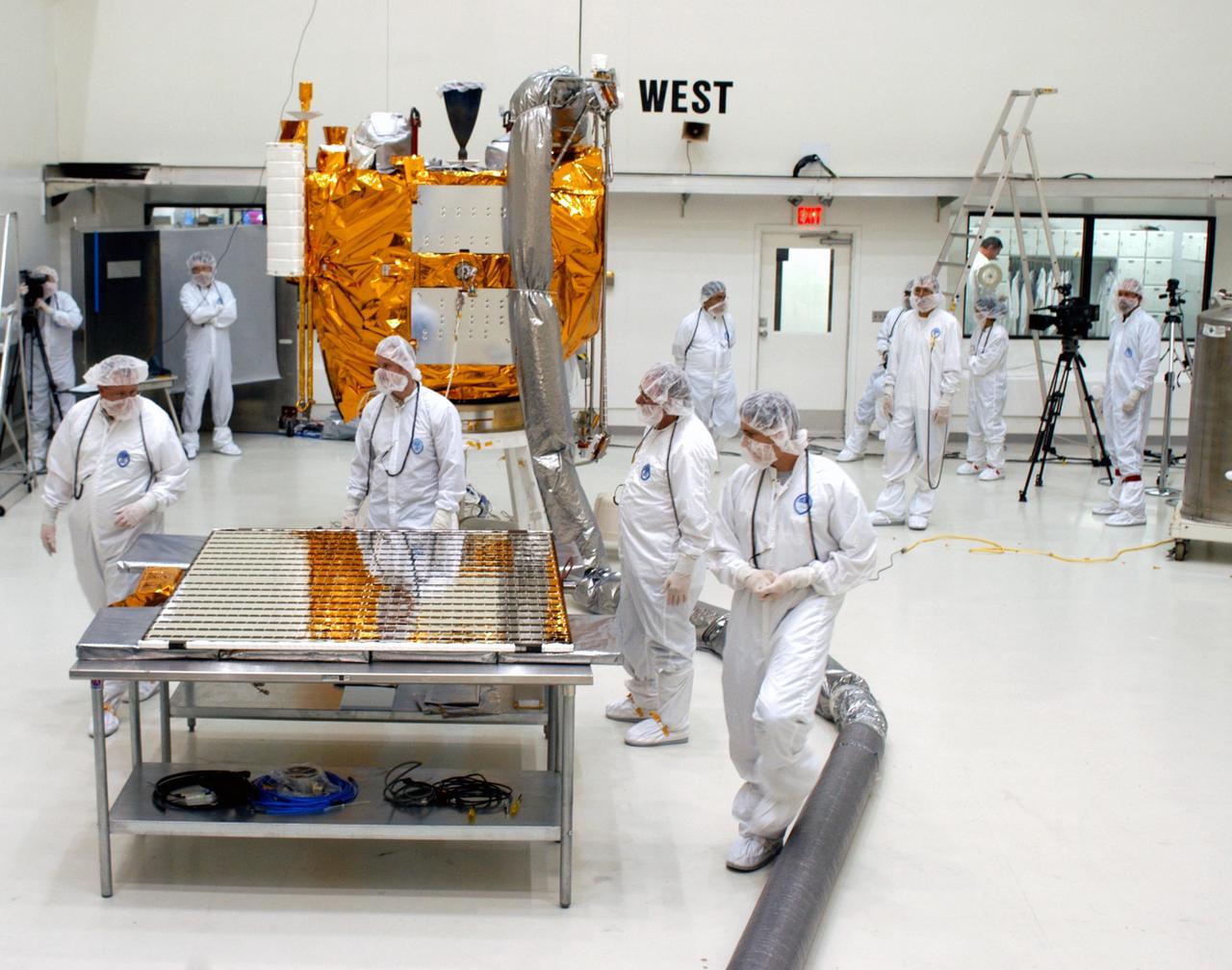 KENNEDY SPACE CENTER, FLA.  - Technicians at Astrotech in Titusville, Fla., look over a solar panel ready to be installed on NASA’s MESSENGER spacecraft.  It is one of two large solar panels, supplemented with a nickel-hydrogen battery, that will provide MESSENGER’s power.  MESSENGER is scheduled to launch Aug. 2 aboard a Boeing Delta II rocket from Pad 17-B, Cape Canaveral Air Force Station, Fla. It will return to Earth for a gravity boost in July 2005, then fly past Venus twice, in October 2006 and June 2007. The spacecraft uses the tug of Venus’ gravity to resize and rotate its trajectory closer to Mercury’s orbit.  Three Mercury flybys, each followed about two months later by a course-correction maneuver, put MESSENGER in position to enter Mercury orbit in March 2011. During the flybys, MESSENGER will map nearly the entire planet in color, image most of the areas unseen by Mariner 10, and measure the composition of the surface, atmosphere and magnetosphere. It will be the first new data from Mercury in more than 30 years - and invaluable for planning MESSENGER’s year-long orbital mission.  MESSENGER was built for NASA by the Johns Hopkins University Applied Physics Laboratory in Laurel, Md.
