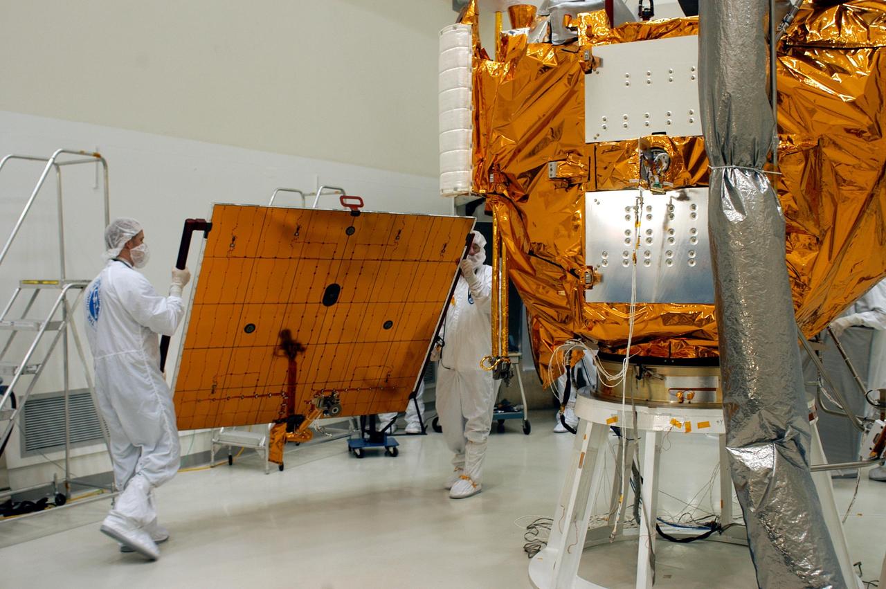 KENNEDY SPACE CENTER, FLA.  - Technicians at Astrotech in Titusville, Fla., carry a solar panel toward NASA’s MESSENGER spacecraft for installation.  It is one of two large solar panels, supplemented with a nickel-hydrogen battery, that will provide MESSENGER’s power.  MESSENGER is scheduled to launch Aug. 2 aboard a Boeing Delta II rocket from Pad 17-B, Cape Canaveral Air Force Station, Fla. It will return to Earth for a gravity boost in July 2005, then fly past Venus twice, in October 2006 and June 2007. The spacecraft uses the tug of Venus’ gravity to resize and rotate its trajectory closer to Mercury’s orbit.  Three Mercury flybys, each followed about two months later by a course-correction maneuver, put MESSENGER in position to enter Mercury orbit in March 2011. During the flybys, MESSENGER will map nearly the entire planet in color, image most of the areas unseen by Mariner 10, and measure the composition of the surface, atmosphere and magnetosphere. It will be the first new data from Mercury in more than 30 years - and invaluable for planning MESSENGER’s year-long orbital mission.  MESSENGER was built for NASA by the Johns Hopkins University Applied Physics Laboratory in Laurel, Md.