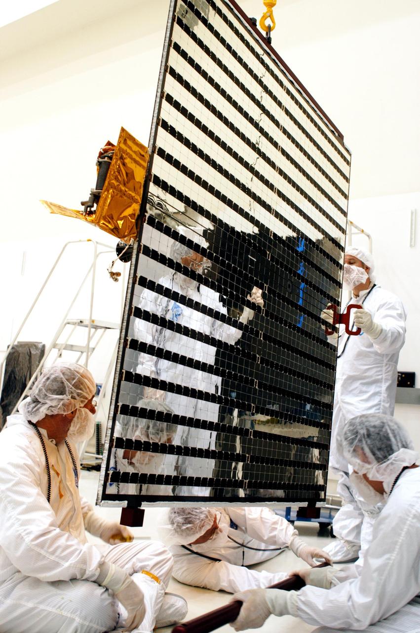 KENNEDY SPACE CENTER, FLA.  - Technicians at Astrotech in Titusville, Fla., adjust a solar panel suspended from above for installation on NASA’s MESSENGER spacecraft.  It is one of two large solar panels, supplemented with a nickel-hydrogen battery, that will provide MESSENGER’s power.  MESSENGER is scheduled to launch Aug. 2 aboard a Boeing Delta II rocket from Pad 17-B, Cape Canaveral Air Force Station, Fla.  It will return to Earth for a gravity boost in July 2005, then fly past Venus twice, in October 2006 and June 2007. The spacecraft uses the tug of Venus’ gravity to resize and rotate its trajectory closer to Mercury’s orbit.  Three Mercury flybys, each followed about two months later by a course-correction maneuver, put MESSENGER in position to enter Mercury orbit in March 2011. During the flybys, MESSENGER will map nearly the entire planet in color, image most of the areas unseen by Mariner 10, and measure the composition of the surface, atmosphere and magnetosphere. It will be the first new data from Mercury in more than 30 years - and invaluable for planning MESSENGER’s year-long orbital mission.  MESSENGER was built for NASA by the Johns Hopkins University Applied Physics Laboratory in Laurel, Md.