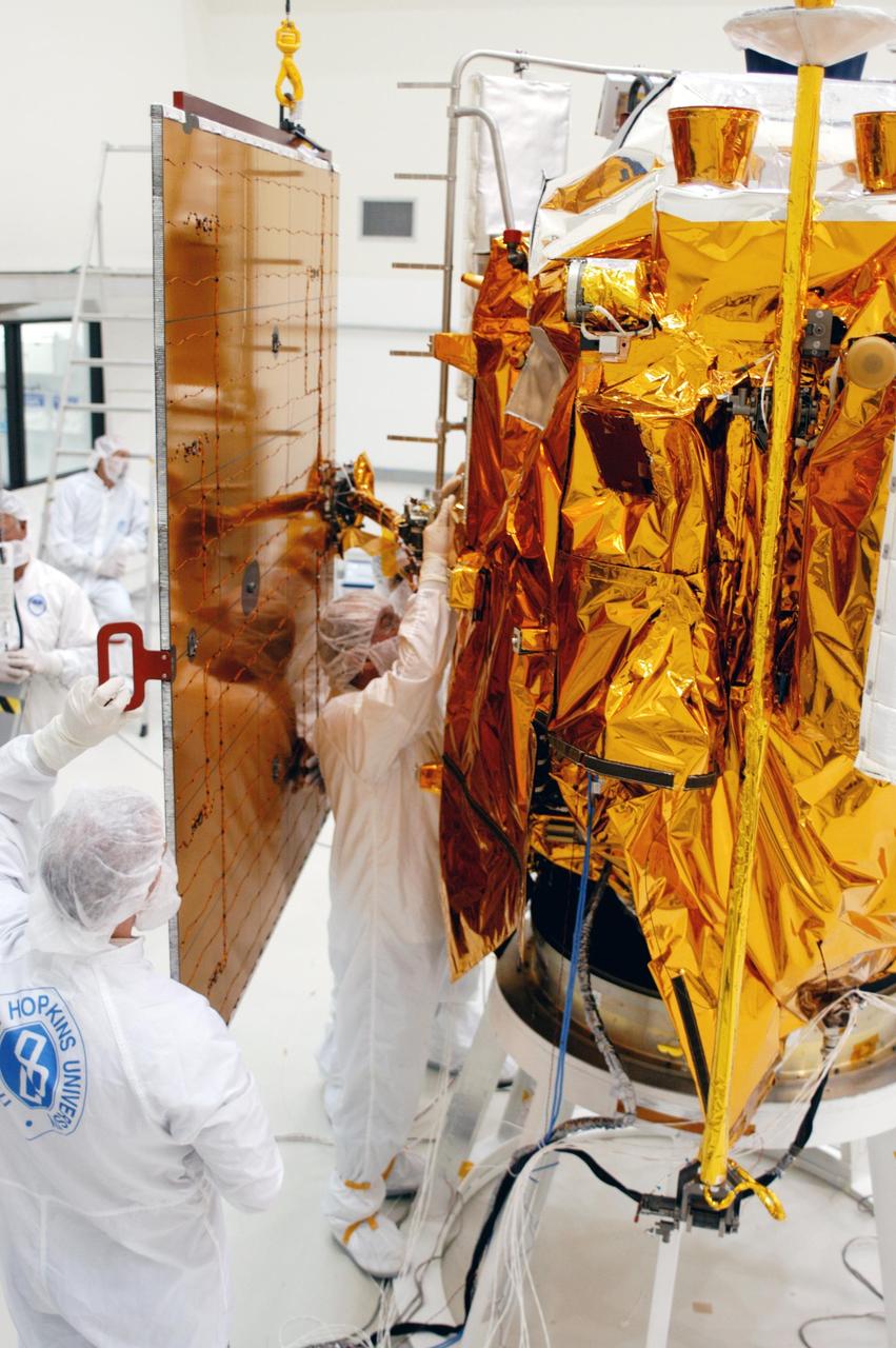 KENNEDY SPACE CENTER, FLA.  - Technicians at Astrotech in Titusville, Fla., steady a solar panel suspended from above as others prepare to install it on NASA’s MESSENGER spacecraft.  It is one of two large solar panels, supplemented with a nickel-hydrogen battery, that will provide MESSENGER’s power.  MESSENGER is scheduled to launch Aug. 2 aboard a Boeing Delta II rocket from Pad 17-B, Cape Canaveral Air Force Station, Fla. It will return to Earth for a gravity boost in July 2005, then fly past Venus twice, in October 2006 and June 2007. The spacecraft uses the tug of Venus’ gravity to resize and rotate its trajectory closer to Mercury’s orbit.  Three Mercury flybys, each followed about two months later by a course-correction maneuver, put MESSENGER in position to enter Mercury orbit in March 2011. During the flybys, MESSENGER will map nearly the entire planet in color, image most of the areas unseen by Mariner 10, and measure the composition of the surface, atmosphere and magnetosphere. It will be the first new data from Mercury in more than 30 years - and invaluable for planning MESSENGER’s year-long orbital mission.  MESSENGER was built for NASA by the Johns Hopkins University Applied Physics Laboratory in Laurel, Md.