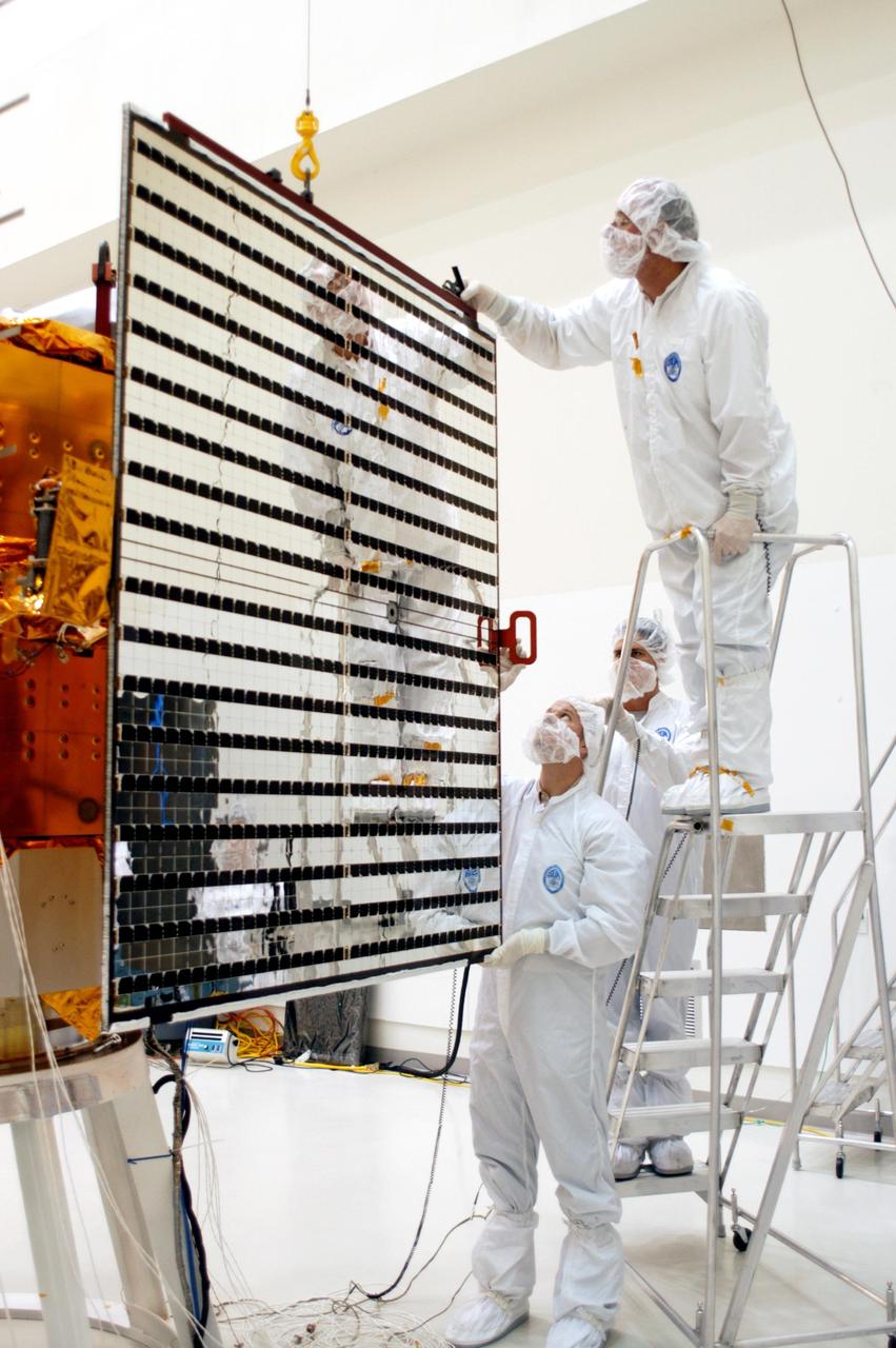 KENNEDY SPACE CENTER, FLA.  - Technicians at Astrotech in Titusville, Fla., guide a solar panel closer to NASA’s MESSENGER spacecraft for installation.  It is one of two large solar panels, supplemented with a nickel-hydrogen battery, that will provide MESSENGER’s power.  MESSENGER is scheduled to launch Aug. 2 aboard a Boeing Delta II rocket from Pad 17-B, Cape Canaveral Air Force Station, Fla. It will return to Earth for a gravity boost in July 2005, then fly past Venus twice, in October 2006 and June 2007. The spacecraft uses the tug of Venus’ gravity to resize and rotate its trajectory closer to Mercury’s orbit.  Three Mercury flybys, each followed about two months later by a course-correction maneuver, put MESSENGER in position to enter Mercury orbit in March 2011. During the flybys, MESSENGER will map nearly the entire planet in color, image most of the areas unseen by Mariner 10, and measure the composition of the surface, atmosphere and magnetosphere. It will be the first new data from Mercury in more than 30 years - and invaluable for planning MESSENGER’s year-long orbital mission.  MESSENGER was built for NASA by the Johns Hopkins University Applied Physics Laboratory in Laurel, Md.