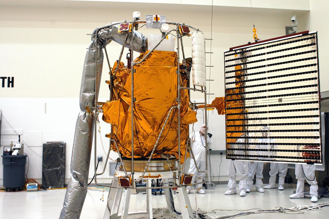 KENNEDY SPACE CENTER, FLA.  - Technicians at Astrotech in Titusville, Fla., help guide  a solar panel toward NASA’s MESSENGER spacecraft for installation.  It is one of two large solar panels, supplemented with a nickel-hydrogen battery, that will provide MESSENGER’s power.  MESSENGER is scheduled to launch Aug. 2 aboard a Boeing Delta II rocket from Pad 17-B, Cape Canaveral Air Force Station, Fla.  It will return to Earth for a gravity boost in July 2005, then fly past Venus twice, in October 2006 and June 2007. The spacecraft uses the tug of Venus’ gravity to resize and rotate its trajectory closer to Mercury’s orbit.  Three Mercury flybys, each followed about two months later by a course-correction maneuver, put MESSENGER in position to enter Mercury orbit in March 2011. During the flybys, MESSENGER will map nearly the entire planet in color, image most of the areas unseen by Mariner 10, and measure the composition of the surface, atmosphere and magnetosphere. It will be the first new data from Mercury in more than 30 years - and invaluable for planning MESSENGER’s year-long orbital mission.  MESSENGER was built for NASA by the Johns Hopkins University Applied Physics Laboratory in Laurel, Md.