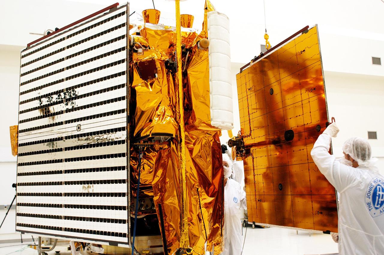 KENNEDY SPACE CENTER, FLA.  - At right, technicians at Astrotech in Titusville, Fla., guide into place the second solar panel to be installed on NASA’s MESSENGER spacecraft.  At left is the first panel already installed.  The two large solar panels, supplemented with a nickel-hydrogen battery, will provide MESSENGER’s power.  MESSENGER is scheduled to launch Aug. 2 aboard a Boeing Delta II rocket from Pad 17-B, Cape Canaveral Air Force Station, Fla. It will return to Earth for a gravity boost in July 2005, then fly past Venus twice, in October 2006 and June 2007. The spacecraft uses the tug of Venus’ gravity to resize and rotate its trajectory closer to Mercury’s orbit.  Three Mercury flybys, each followed about two months later by a course-correction maneuver, put MESSENGER in position to enter Mercury orbit in March 2011. During the flybys, MESSENGER will map nearly the entire planet in color, image most of the areas unseen by Mariner 10, and measure the composition of the surface, atmosphere and magnetosphere. It will be the first new data from Mercury in more than 30 years - and invaluable for planning MESSENGER’s year-long orbital mission.  MESSENGER was built for NASA by the Johns Hopkins University Applied Physics Laboratory in Laurel, Md.