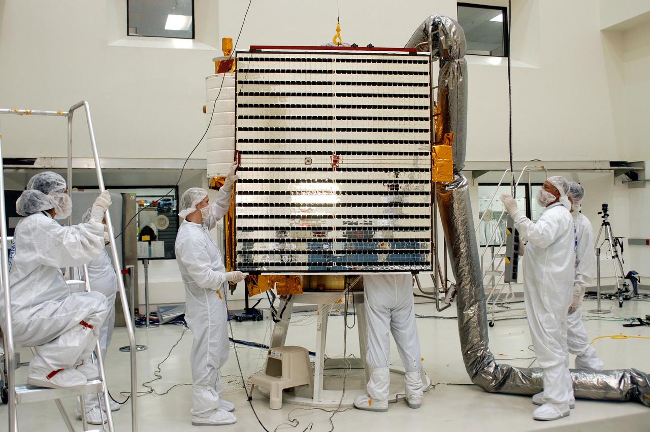 KENNEDY SPACE CENTER, FLA.  - Technicians at Astrotech in Titusville, Fla., hold steady the second solar panel being installed on NASA’s MESSENGER spacecraft.  At left is the first panel already installed.  The two large solar panels, supplemented with a nickel-hydrogen battery, will provide MESSENGER’s power.  MESSENGER is scheduled to launch Aug. 2 aboard a Boeing Delta II rocket from Pad 17-B, Cape Canaveral Air Force Station, Fla. It will return to Earth for a gravity boost in July 2005, then fly past Venus twice, in October 2006 and June 2007. The spacecraft uses the tug of Venus’ gravity to resize and rotate its trajectory closer to Mercury’s orbit.  Three Mercury flybys, each followed about two months later by a course-correction maneuver, put MESSENGER in position to enter Mercury orbit in March 2011. During the flybys, MESSENGER will map nearly the entire planet in color, image most of the areas unseen by Mariner 10, and measure the composition of the surface, atmosphere and magnetosphere. It will be the first new data from Mercury in more than 30 years - and invaluable for planning MESSENGER’s year-long orbital mission.  MESSENGER was built for NASA by the Johns Hopkins University Applied Physics Laboratory in Laurel, Md.