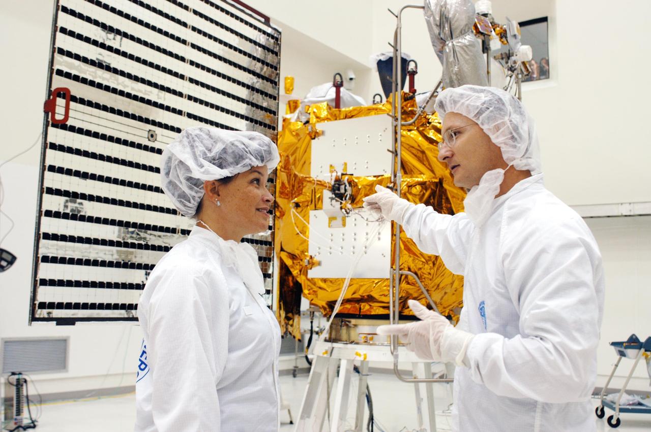 KENNEDY SPACE CENTER, FLA.  - At Astrotech in Titusville, Fla.,  NASA Mission Integration Manager Cheryle Mako and NASA Launch Site Integration Manager John Hueckel talk before the deployment of the solar array panels on the MESSENGER spacecraft behind them.  The solar arrays will provide MESSENGER’s power on its journey to Mercury.   MESSENGER is scheduled to launch Aug. 2 aboard a Boeing Delta II rocket from Pad 17-B, Cape Canaveral Air Force Station, Fla. It will return to Earth for a gravity boost in July 2005, then fly past Venus twice, in October 2006 and June 2007. The spacecraft uses the tug of Venus’ gravity to resize and rotate its trajectory closer to Mercury’s orbit.  Three Mercury flybys, each followed about two months later by a course-correction maneuver, put MESSENGER in position to enter Mercury orbit in March 2011. During the flybys, MESSENGER will map nearly the entire planet in color, image most of the areas unseen by Mariner 10, and measure the composition of the surface, atmosphere and magnetosphere. It will be the first new data from Mercury in more than 30 years - and invaluable for planning MESSENGER’s year-long orbital mission.  MESSENGER was built for NASA by APL in Laurel, Md.