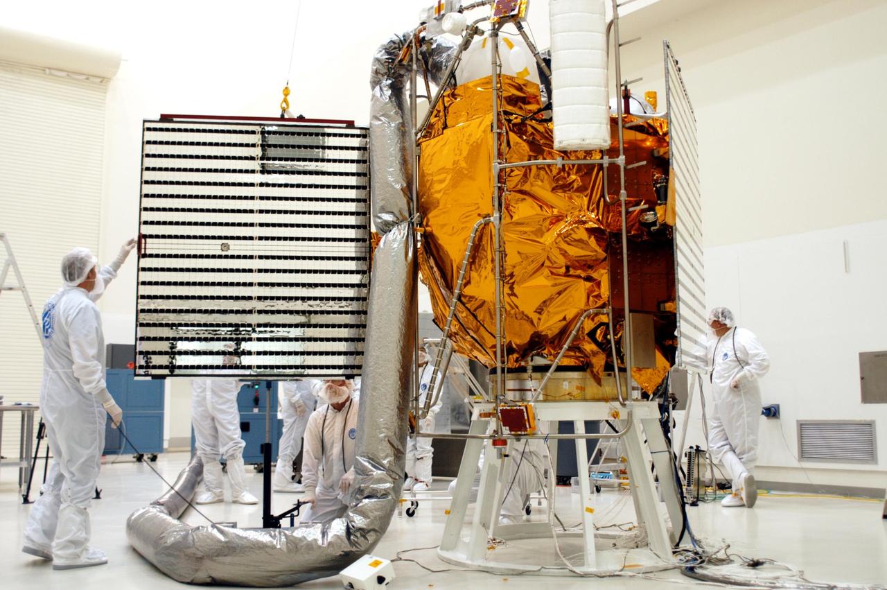 KENNEDY SPACE CENTER, FLA.  - At Astrotech in Titusville, Fla., technicians with The Johns Hopkins University Applied Physics Laboratory (APL) check one of two solar panels on the MESSENGER spacecraft after a deployment test.  The other panel is at right, undeployed.  The solar arrays will provide MESSENGER’s power on its journey to Mercury.   MESSENGER is scheduled to launch Aug. 2 aboard a Boeing Delta II rocket from Pad 17-B, Cape Canaveral Air Force Station, Fla. It will return to Earth for a gravity boost in July 2005, then fly past Venus twice, in October 2006 and June 2007. The spacecraft uses the tug of Venus’ gravity to resize and rotate its trajectory closer to Mercury’s orbit.  Three Mercury flybys, each followed about two months later by a course-correction maneuver, put MESSENGER in position to enter Mercury orbit in March 2011. During the flybys, MESSENGER will map nearly the entire planet in color, image most of the areas unseen by Mariner 10, and measure the composition of the surface, atmosphere and magnetosphere. It will be the first new data from Mercury in more than 30 years - and invaluable for planning MESSENGER’s year-long orbital mission.  MESSENGER was built for NASA by APL in Laurel, Md.