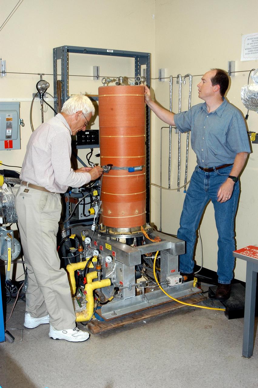 KENNEDY SPACE CENTER, FLA. -  James E. Fesmire (right), NASA lead engineer for the KSC Cryogenics Testbed, works on Cryostat-1, the Methods of Testing Thermal Insulation and Association Test Apparatus, which he developed.  At left is co-inventor Dr. Stan Augustynowicz, chief scientist with Sierra Lobo Inc. in Milan, Ohio. Cryostat-1 provides absolute thermal performance values of cryogenic insulation systems under real-world conditions. Cryogenic liquid is supplied to a test chamber and two guard chambers, and temperatures are sensed within the vacuum chamber to test aerogels, foams or other materials.   The Cryostat-1 machine can detect the absolute heat leakage rates through materials under the full range of vacuum conditions.  Fesmire recently acquired three patents for testing thermal insulation materials for cryogenic systems. The research team of the Cryogenics Testbed offers testing and support for a number of programs and initiatives for NASA and commercial customers.