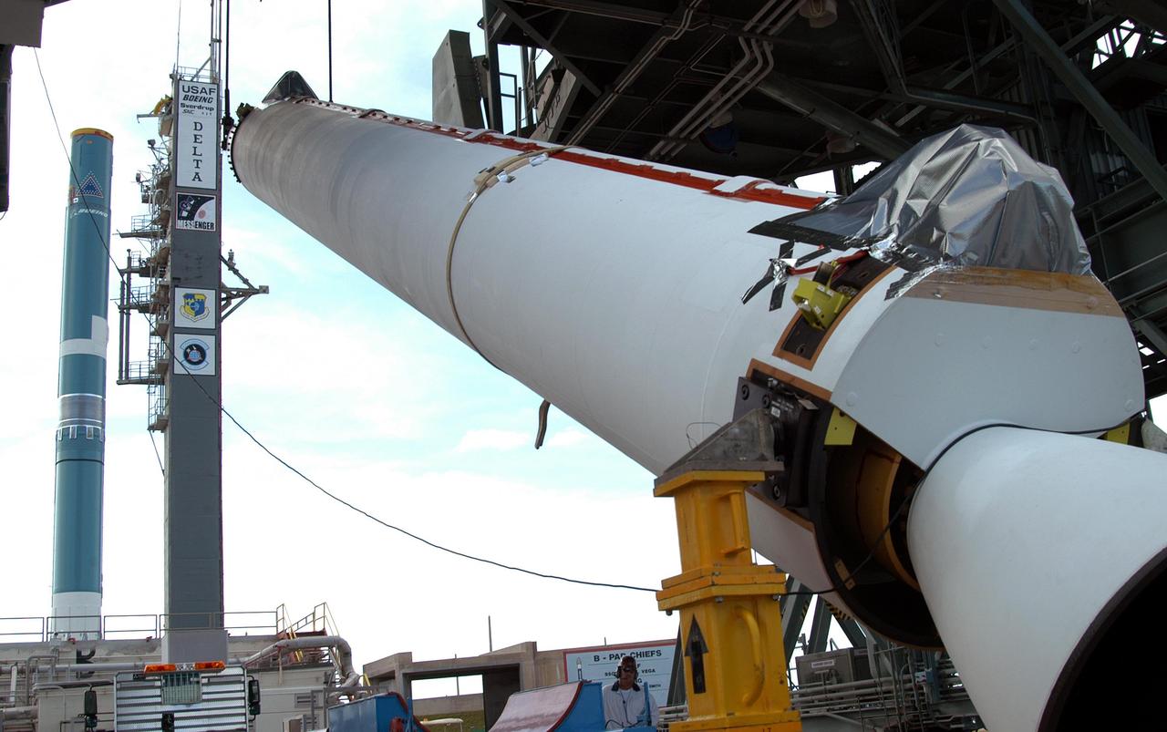 KENNEDY SPACE CENTER, FLA. -  At Pad 17-B, Cape Canaveral Air Force Station, the first Solid Rocket Booster  (SRB) for the MESSENGER spacecraft launch is raised from the transporter.  The SRB will be mated to the Boeing Delta II Heavy rocket, seen at left, for the Aug. 2 launch of MESSENGER to the planet Mercury.  The spacecraft is expected to reach orbit around Mercury in March 2011.  MESSENGER was built for NASA by the Johns Hopkins University Applied Physics Laboratory in Laurel, Md.