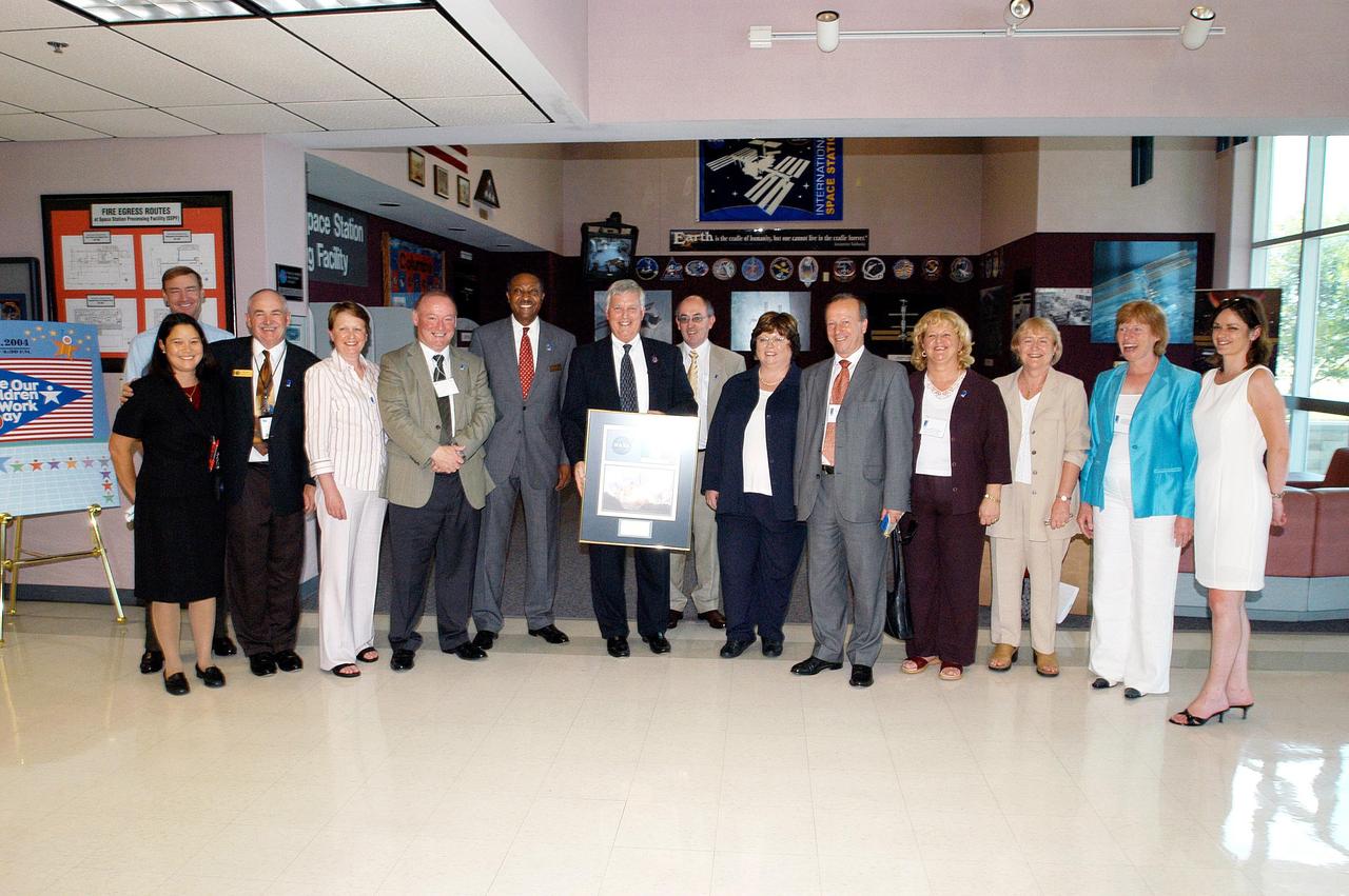 KENNEDY SPACE CENTER, FLA. - In the Space Station Processing Facility, Center Director Jim Kennedy holds a framed photo to be presented to Mary Harney , Tanaiste (Deputy Prime Minister) and Minister for Enterprise, Trade and Employment of Ireland (at his left). Harney is visiting KSC to support a Memorandum of Understanding between Florida Spaceport Authority and the Irish government’s training and employment authority (FAS). The joint initiative enables Irish students to work with science and engineering experts during a six-week program in Florida. On Kennedy’s right is FSA Director Capt. Winston Scott. Next to Harney is Paul Haran, secretary to the deputy prime minister. Gathered here with Harney, Haran, Kennedy and Scott are Bridget Flynn, assistant to Harney; Brian Joseph Geoghegan, director of FAS; Roderick Peter Molloy, director general of FAS, and Noreen Molloy, his wife; Caitriona White, FAS public relations manager; Anne Haran; and Roisin McCann, Dept. of Enterprise, Trade and Employment.