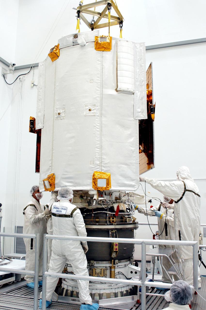 KENNEDY SPACE CENTER, FLA. - Technicians at Astrotech Space Operations in Titusville, Fla., work on the back side of the MESSENGER spacecraft, mating it with the Payload Assist Module, the Boeing Delta II third stage, below. The white panel seen here is the heat-resistant, ceramic cloth sunshade that will enable MESSENGER to operate at room temperature. MESSENGER (Mercury Surface, Space Environment, Geochemistry and Ranging) is scheduled to launch Aug. 2 aboard a Boeing Delta II rocket from Pad 17-B, Cape Canaveral Air Force Station, Fla. It will return to Earth for a gravity boost in July 2005, then fly past Venus twice, in October 2006 and June 2007. It is expected to enter Mercury orbit in March 2011. MESSENGER was built for NASA by the Johns Hopkins University Applied Physics Laboratory in Laurel, Md.