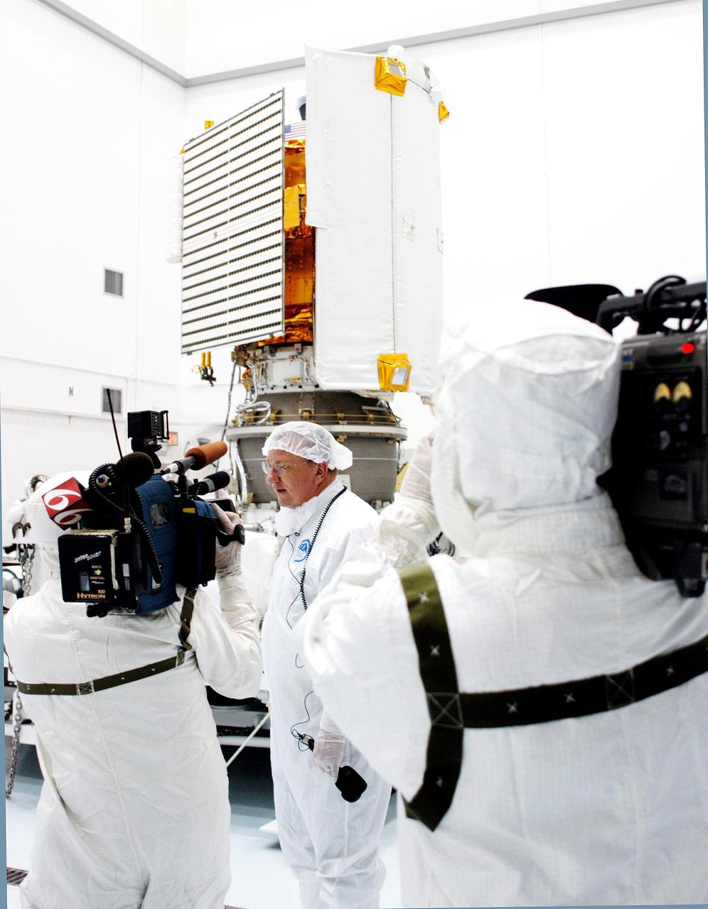 KENNEDY SPACE CENTER, FLA. - At Astrotech Space Operations in Titusville, Fla., members of the media, wearing clean room suits, gather around Ted Hartka, MESSENGER lead mechanical engineer, with The Johns Hopkins  University Applied Physics Laboratory (APL).  Hartka is talking about the MESSENGER spacecraft’s mission to Mercury.  The spacecraft, mated to the Delta II third stage Payload Assist Module, is in the background. MESSENGER is scheduled to launch Aug. 2 aboard a Boeing Delta II rocket from Pad 17-B, Cape Canaveral Air Force Station, Fla.