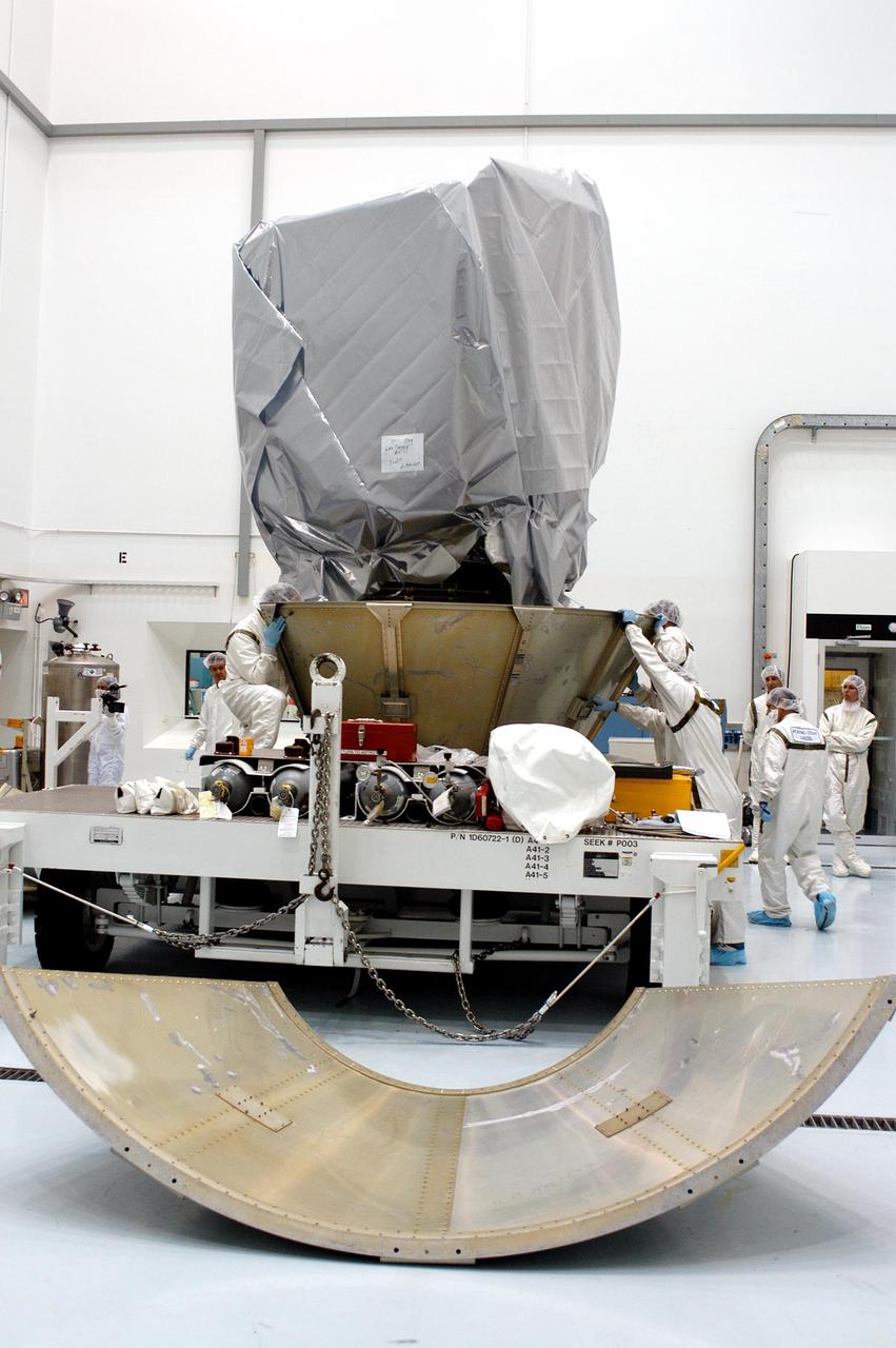 KENNEDY SPACE CENTER, FLA. - Boeing workers at Astrotech Space Operations in Titusville, Fla., secure the first part of a transportation canister around the Delta II upper stage booster on the MESSENGER (Mercury Surface, Space Environment, Geochemistry and Ranging) spacecraft.  Another panel waits in front of the work stand.  MESSENGER will be transferred to Launch Pad 17-B at Cape Canaveral Air Force Station, Fla.  Liftoff of MESSENGER aboard a Boeing Delta II Heavy rocket is scheduled for Aug. 2.  The spacecraft is expected to reach orbit around the planet in March 2011.  MESSENGER was built for NASA by the Johns Hopkins University Applied Physics Laboratory in Laurel, Md.