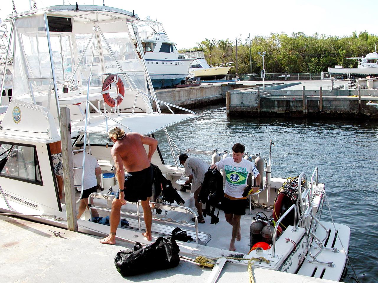 KENNEDY SPACE CENTER, FLA. - Disembarking from the boat in Key Largo are Otto Rutten and Marc Reagan, participating in the NASA Extreme Environment Mission Operations 6 (NEEMO-6) mission at the NOAA Aquarius underwater station offshore.  Rutten is director for the National Underwater Research Center; Reagan is mission lead.  The NEEMO-6 mission involves exposing an astronaut/scientist crew to a real mission experience in an extreme environment to prepare for future space flight.  Spacewalk-like diving excursions and field-tests on a variety of biomedical equipment are designed to help astronauts living aboard the International Space Station.  The NEEMO-6 team comprises astronaut John Herrington, mission commander, astronauts Doug Wheelock and Nick Patrick, and biomedical engineer Tara Ruttley. To prepare for their 10-day stay, the team had dive training twice a day at the Life Support Buoy, anchored above Aquarius.