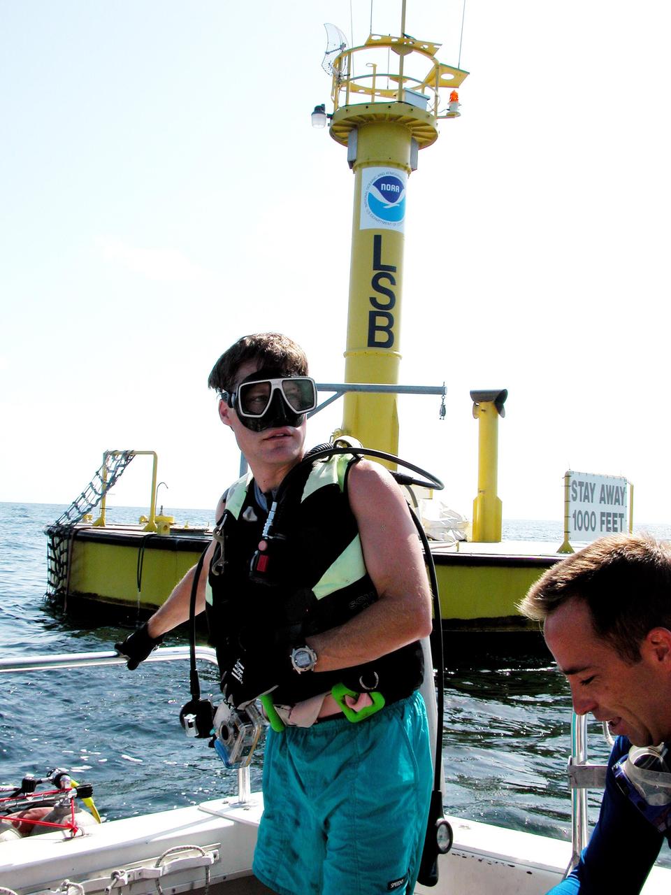KENNEDY SPACE CENTER, FLA. - Onboard the dive boat at the Life Support Buoy offshore from Key Largo is Marc Reagan, mission lead for the NASA Extreme Environment Mission Operations 6 (NEEMO-6) mission.  At right is Lt. Scott Sparks, a Navy medical officer.  Reagan is also the underwater still photographer.  The NEEMO-6 team comprises John Herrington, commander, Tara Ruttley, a biomedical engineer, and astronauts Nick Patrick and Doug Wheelock.  The NEEMO-6 mission involves exposing an astronaut/scientist crew to a real mission experience in an extreme environment - the NOAA undersea station Aquarius - to prepare for future space flight.  Spacewalk-like diving excursions and field-tests on a variety of biomedical equipment are designed to help astronauts living aboard the International Space Station.  To prepare for their 10-day stay, the team had dive training twice a day at the Life Support Buoy, anchored above Aquarius.