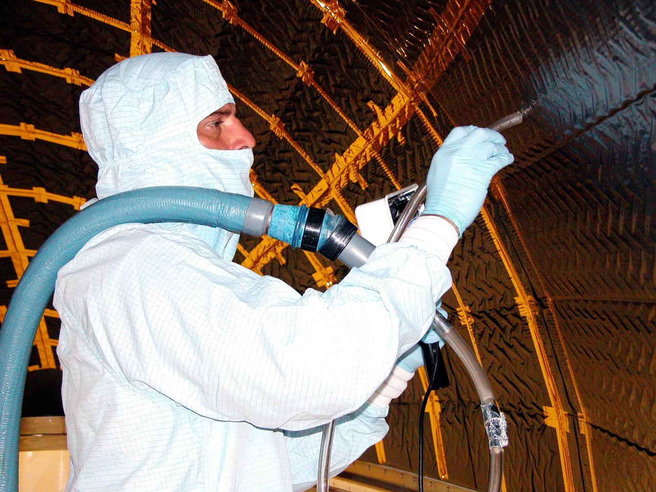 KENNEDY SPACE CENTER, FLA. - Workers in Hangar AE, Cape Canaveral Air Force Station, meticulously clean the inside of a Boeing Delta fairing that will encapsulate the Swift spacecraft. Swift is a first-of-its-kind, multi-wavelength observatory dedicated to the study of gamma-ray burst (GRB) science. Its three instruments will work together to observe GRBs and afterglows in the gamma-ray, X-ray and optical wavebands. Swift is part of NASA’s medium explorer (MIDEX) program being developed by an international collaboration. It will be launched into a low-Earth orbit on a Delta 7320 rocket in October 2004. During its nominal 2-year mission, Swift is expected to observe more than 200 bursts, which will represent the most comprehensive study of GRB afterglow to date.