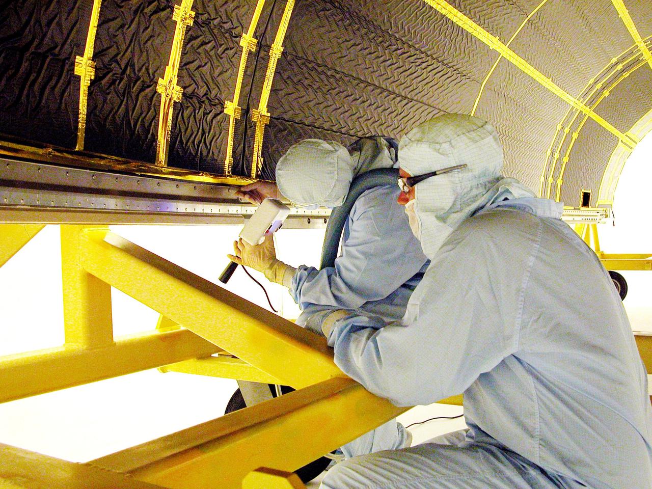 KENNEDY SPACE CENTER, FLA. - Workers in Hangar AE, Cape Canaveral Air Force Station, meticulously clean the inside of a Boeing Delta fairing that will encapsulate the Swift spacecraft. Swift is a first-of-its-kind, multi-wavelength observatory dedicated to the study of gamma-ray burst (GRB) science. Its three instruments will work together to observe GRBs and afterglows in the gamma-ray, X-ray and optical wavebands. Swift is part of NASA’s medium explorer (MIDEX) program being developed by an international collaboration. It will be launched into a low-Earth orbit on a Delta 7320 rocket in October 2004. During its nominal 2-year mission, Swift is expected to observe more than 200 bursts, which will represent the most comprehensive study of GRB afterglow to date.