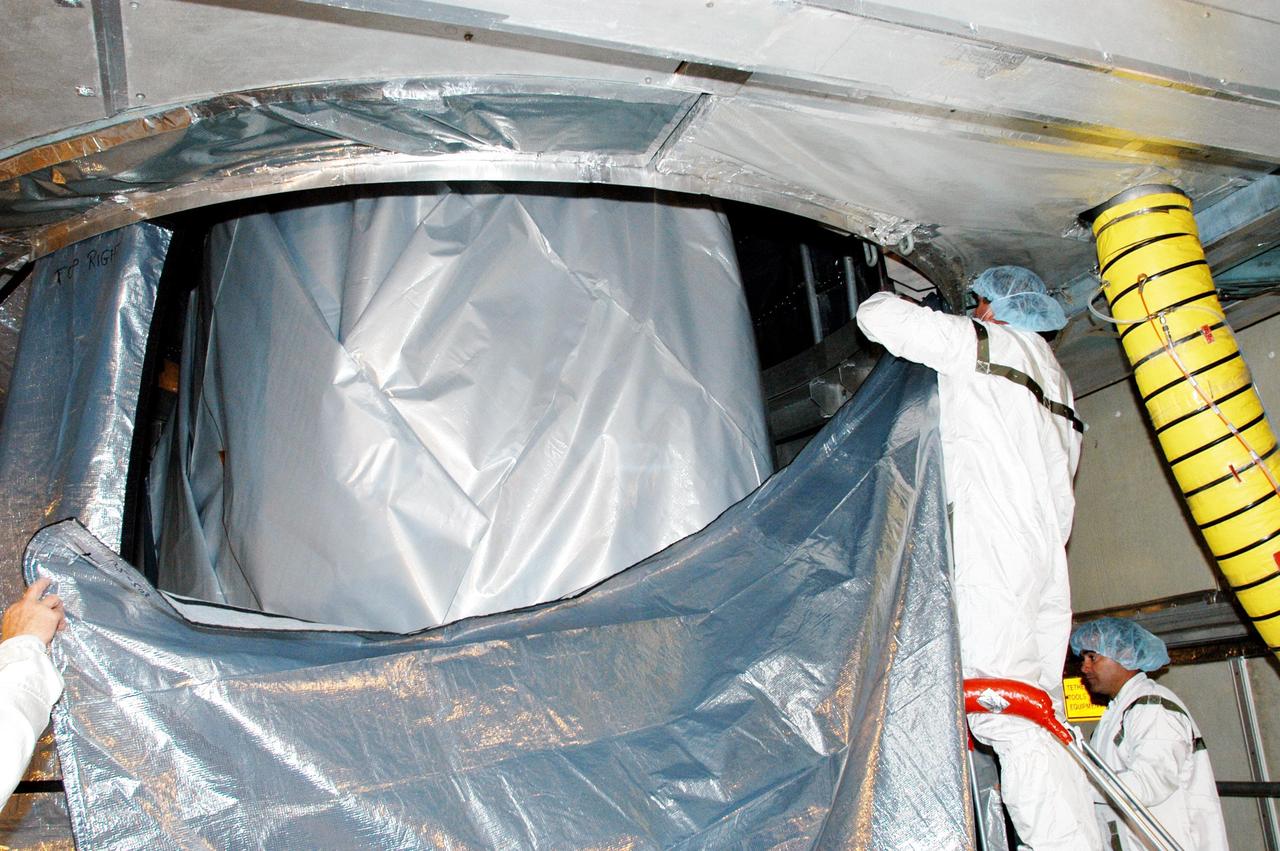 KENNEDY SPACE CENTER, FLA. - In the mobile service tower at Launch Complex 17-B, Cape Canaveral Air Force Station, workers place an environmental curtain around the MESSENGER (Mercury Surface, Space Environment, Geochemistry and Ranging) spacecraft, which is still wrapped from its journey to the pad. Scheduled to launch Aug. 2, MESSENGER will return to Earth for a gravity boost in July 2005, then fly past Venus twice, in October 2006 and June 2007. It is expected to enter Mercury orbit in March 2011. MESSENGER was built for NASA by the Johns Hopkins University Applied Physics Laboratory in Laurel, Md. Processing is being done at Astrotech Space Operations in Titusville, Fla.