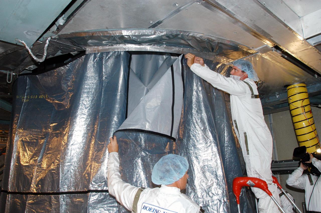 KENNEDY SPACE CENTER, FLA. - In the mobile service tower at Launch Complex 17-B, Cape Canaveral Air Force Station, workers suspend an environmental curtain around the MESSENGER (Mercury Surface, Space Environment, Geochemistry and Ranging) spacecraft, which is still wrapped from its journey to the pad. Scheduled to launch Aug. 2, MESSENGER will return to Earth for a gravity boost in July 2005, then fly past Venus twice, in October 2006 and June 2007. It is expected to enter Mercury orbit in March 2011. MESSENGER was built for NASA by the Johns Hopkins University Applied Physics Laboratory in Laurel, Md. Processing is being done at Astrotech Space Operations in Titusville, Fla.
