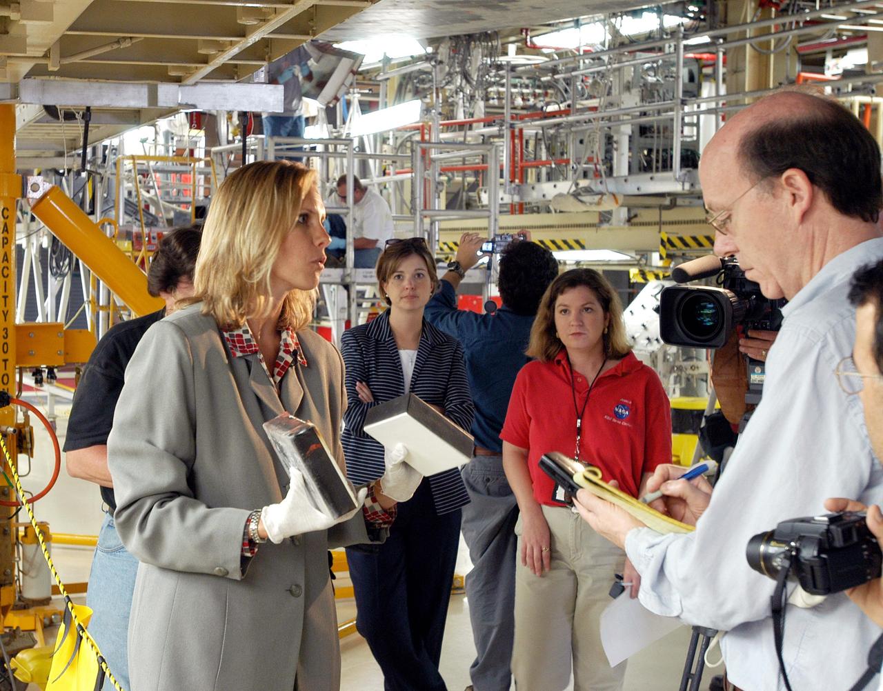 KENNEDY SPACE CENTER, FLA. -   Stephanie Stilson (left), NASA Vehicle Manager, briefs the media attending an informative workshop and tour of the Orbiter Processing Facility (OPF) housing the Space Shuttle Discovery at KSC. During this event, the media received the latest information on Discovery’s processing and viewed workers preparing the vehicle for its safe return to flight scheduled for a launch planning window of March 2005.  Kicking off the activities at the Press Site Auditorium, technical experts led two workshops addressing Reinforced Carbon-Carbon and vehicle instrumentation.  During the tour of the OPF, reporters saw work in progress on Discovery, including reinstallation of the Reinforced Carbon-Carbon panels on the Shuttle's wing leading edge, wiring inspections and instrumentation updates being completed for Return to Flight.