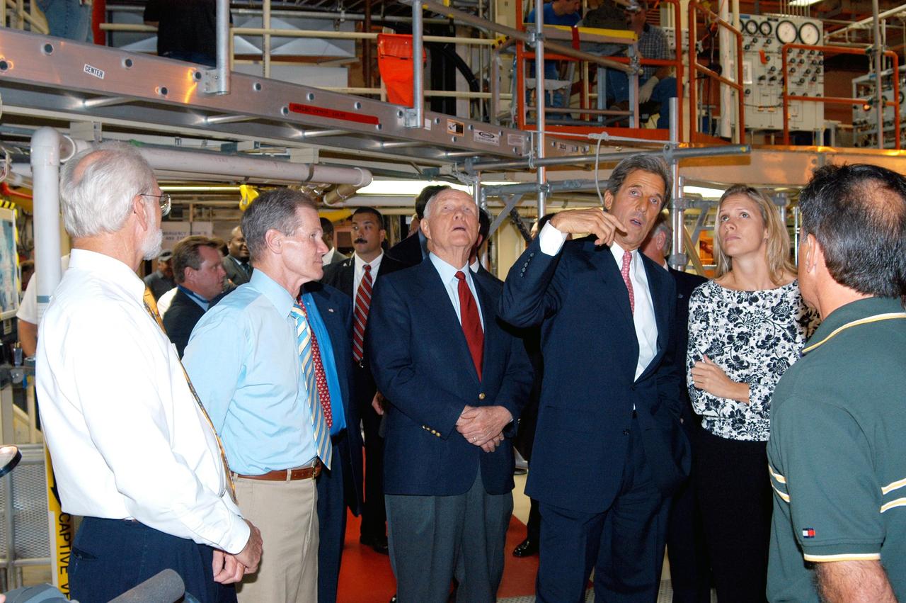 KENNEDY SPACE CENTER, FLA. - Sen. Bill Nelson (second from left), D-Fla., former astronaut and Sen. John H. Glenn, D-Ohio, and Sen. John F. Kerry, D-Mass., receive a briefing from NASA Vehicle Manager Stephanie Stilson during a tour of the Orbiter Processing Facility (OPF). They are standing under the orbiter Discovery, which is being prepared for flight on the next Space Shuttle mission. The tour follows a public meeting Kerry held at the Dr. Kurt H. Debus Conference Facility at the Kennedy Space Center Visitor Complex.  He said he chose to speak at KSC because it symbolizes America’s commitment to science, innovation and technology. He and Sen. John Edwards, D-N.C., are on a speaking tour prior to their appearance at the Democratic National Convention in Boston.