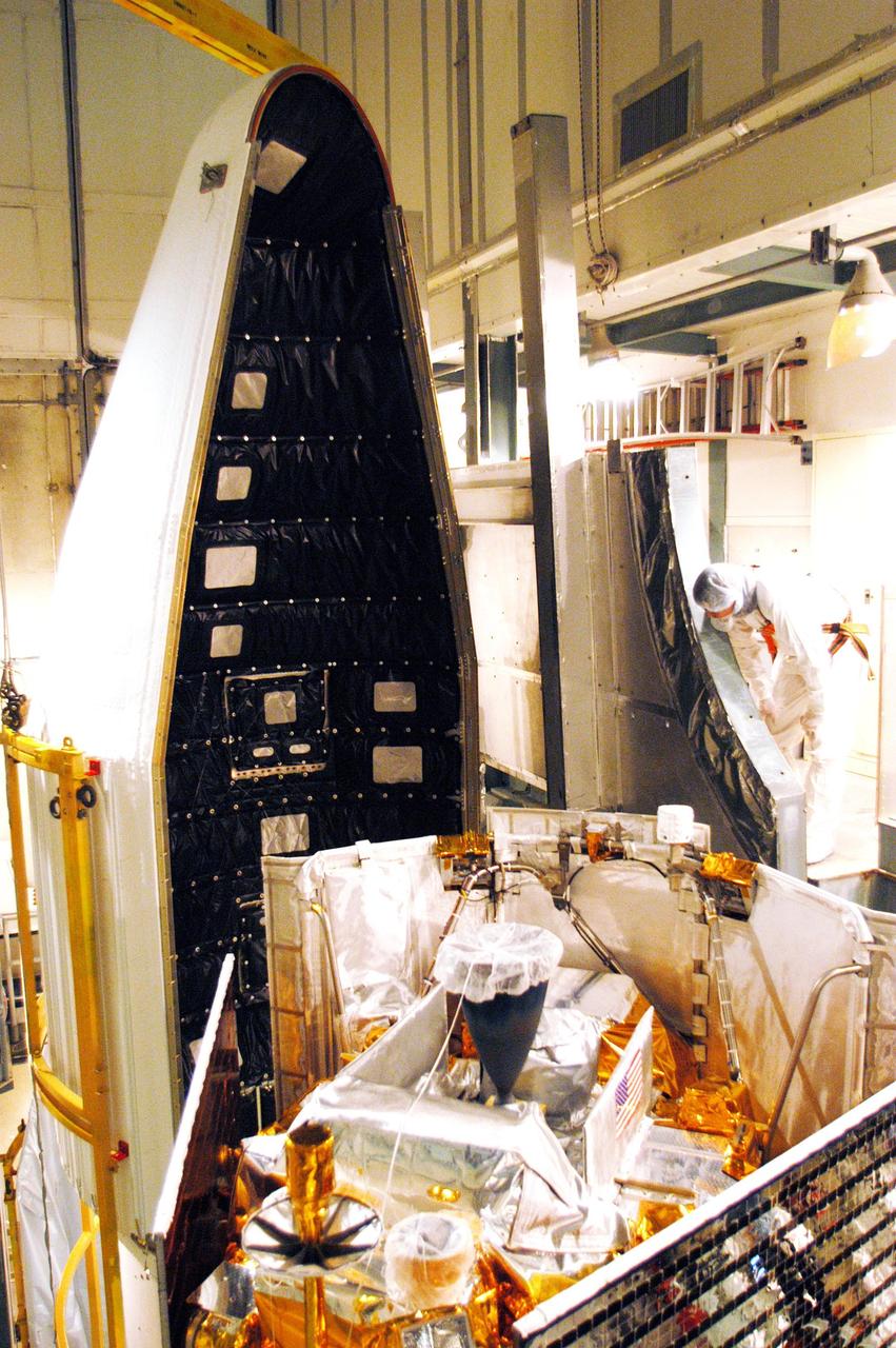 KENNEDY SPACE CENTER, FLA. - On Launch Pad 17-B at Cape Canaveral Air Force Station, the first half of the fairing, at left, is moved into place for installation around the MESSENGER (Mercury Surface, Space Environment, Geochemistry and Ranging) spacecraft.  The fairing is a molded structure that fits flush with the outside surface of the upper stage booster and forms an aerodynamically smooth joint, protecting the spacecraft during launch.  MESSENGER  is scheduled to launch Aug. 2 aboard a Boeing Delta II rocket and is expected to enter Mercury orbit in March 2011.  MESSENGER was built for NASA by the Johns Hopkins University Applied Physics Laboratory in Laurel, Md.