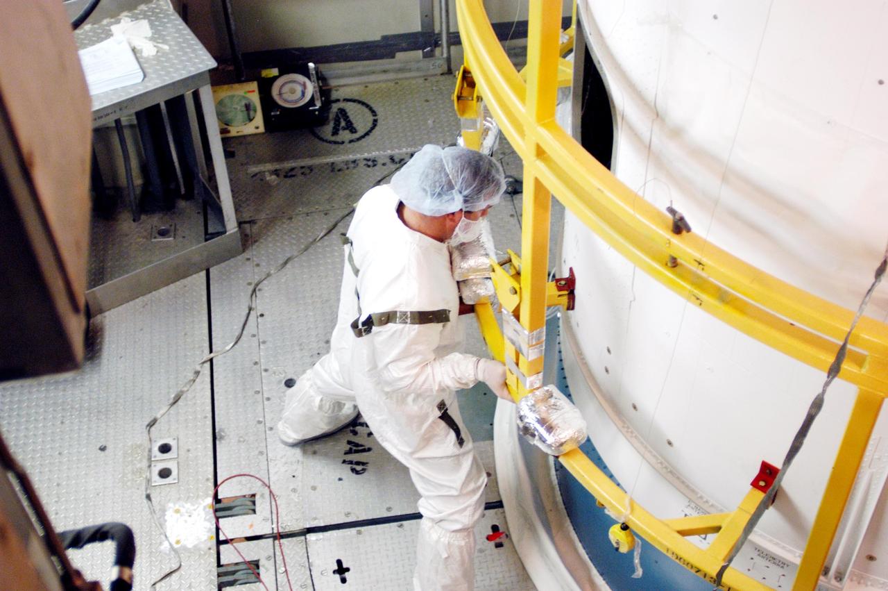 KENNEDY SPACE CENTER, FLA. - On Launch Pad 17-B at Cape Canaveral Air Force Station, Boeing workers secure the first half of the fairing installed around the MESSENGER (Mercury Surface, Space Environment, Geochemistry and Ranging) spacecraft. The fairing is a molded structure that fits flush with the outside surface of the upper stage booster and forms an aerodynamically smooth joint, protecting the spacecraft during launch. MESSENGER is scheduled to launch Aug. 2 aboard a Boeing Delta II rocket and is expected to enter Mercury orbit in March 2011. MESSENGER was built for NASA by the Johns Hopkins University Applied Physics Laboratory in Laurel, Md.