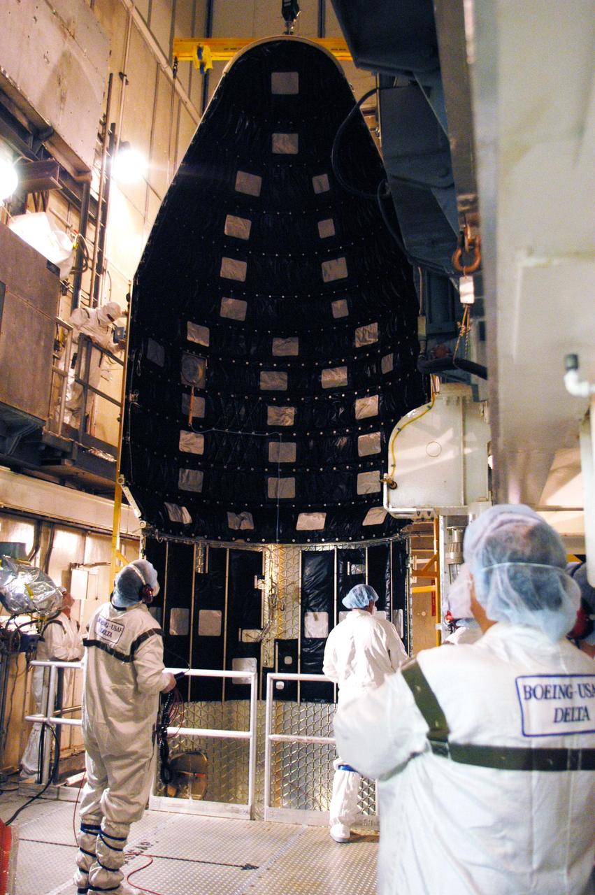 KENNEDY SPACE CENTER, FLA. - On a platform inside the mobile service tower on Launch Pad 17-B at Cape Canaveral Air Force Station, a Boeing worker guides the second half of the fairing as it moves into place around the MESSENGER (Mercury Surface, Space Environment, Geochemistry and Ranging) spacecraft.  The fairing is a molded structure that fits flush with the outside surface of the upper stage booster and forms an aerodynamically smooth joint, protecting the spacecraft during launch.  MESSENGER  is scheduled to launch Aug. 2 aboard a Boeing Delta II rocket and is expected to enter Mercury orbit in March 2011.  MESSENGER was built for NASA by the Johns Hopkins University Applied Physics Laboratory in Laurel, Md.
