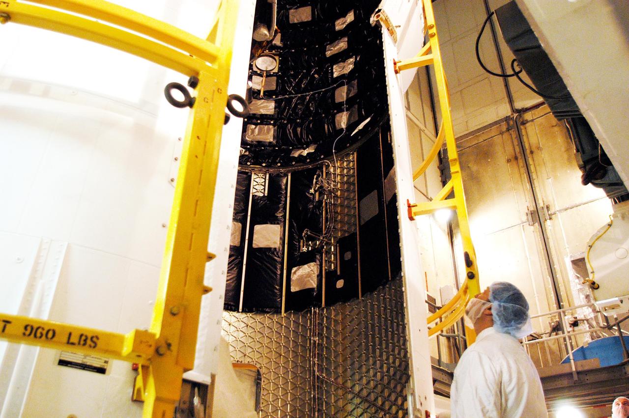 KENNEDY SPACE CENTER, FLA. - On Launch Pad 17-B at Cape Canaveral Air Force Station, a Boeing worker observes the second half of the fairing as it moves into place around the MESSENGER (Mercury Surface, Space Environment, Geochemistry and Ranging) spacecraft.  The fairing is a molded structure that fits flush with the outside surface of the upper stage booster and forms an aerodynamically smooth joint, protecting the spacecraft during launch.  MESSENGER  is scheduled to launch Aug. 2 aboard a Boeing Delta II rocket and is expected to enter Mercury orbit in March 2011.  MESSENGER was built for NASA by the Johns Hopkins University Applied Physics Laboratory in Laurel, Md.