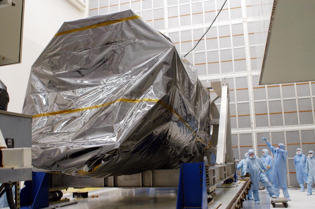 KENNEDY SPACE CENTER, FLA. - Inside Hangar AE at Cape Canaveral Air Force Station (CCAFS), workers observe the canister being lifted from the Swift spacecraft, which is enclosed in a protective cover. Swift is a first-of-its-kind, multi-wavelength observatory dedicated to the study of gamma-ray burst (GRB) science. Its three instruments will work together to observe GRBs and afterglows in the gamma-ray, X-ray and optical wavebands. Swift is part of NASA’s medium explorer (MIDEX) program being developed by an international collaboration. It will be launched no earlier than Oct. 7 into a low-Earth orbit on a Boeing Delta 7320 rocket from pad 17-A at CCAFS. During its nominal 2-year mission, Swift is expected to observe more than 200 bursts, which will represent the most comprehensive study of GRB afterglow to date.