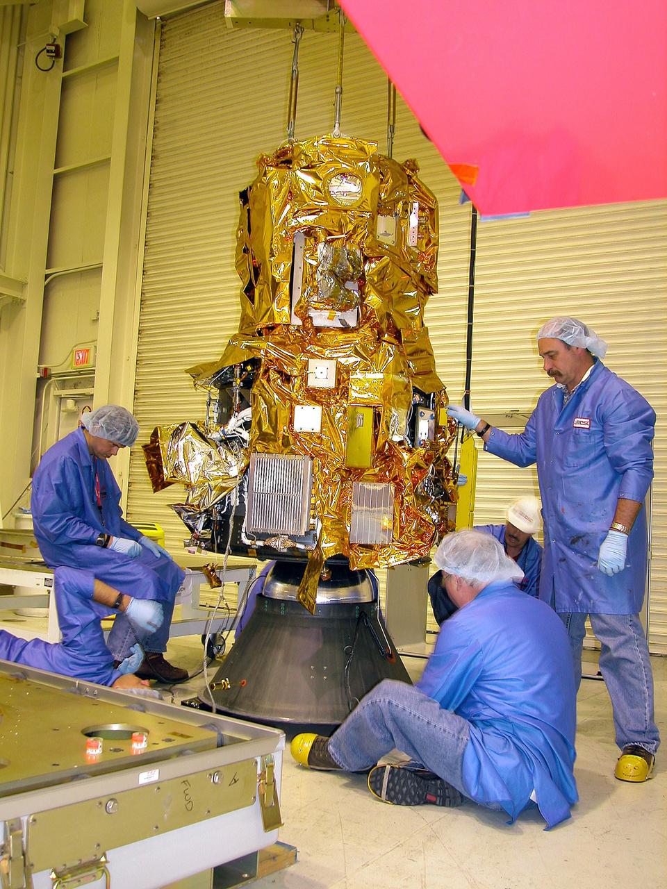 KENNEDY SPACE CENTER, FLA. - At Vandenberg Air Force Base in California, Orbital Sciences technicians observe closely the movement of the DART (Demonstration for Autonomous Rendezvous Technology) flight demonstrator as it is lowered onto a stand.  The spacecraft was developed to prove technologies for locating and maneuvering near an orbiting satellite.  Future applications of technologies developed by the DART project will benefit the nation in future space-vehicle systems development requiring in-space assembly, services or other autonomous rendezvous operations.  Designed and developed for NASA by Orbital Sciences Corporation in Dulles, Va., the DART spacecraft will be launched on a Pegasus launch vehicle. At about 40,000 feet over the Pacific Ocean, the Pegasus will be released from Orbital’s Stargazer L-1011 aircraft, fire its rocket motors and boost DART into a polar orbit approximately 472 miles by 479 miles. Once in orbit, DART will rendezvous with a target satellite, the Multiple Paths, Beyond-Line-of-Site Communications satellite, also built by Orbital Sciences. DART will then perform several close proximity operations, such as moving toward and away from the satellite using navigation data provided by onboard sensors.  DART is scheduled for launch no earlier than Oct. 18.