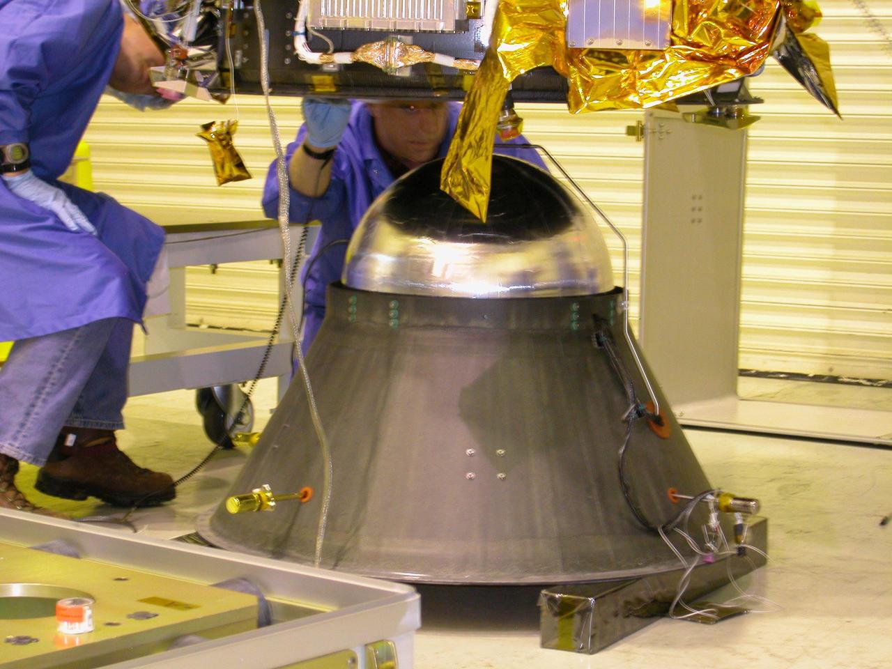 KENNEDY SPACE CENTER, FLA. - At Vandenberg Air Force Base in California, Orbital Sciences technicians watch closely as the DART (Demonstration for Autonomous Rendezvous Technology) flight demonstrator is lowered onto a stand.  The spacecraft was developed to prove technologies for locating and maneuvering near an orbiting satellite.  Future applications of technologies developed by the DART project will benefit the nation in future space-vehicle systems development requiring in-space assembly, services or other autonomous rendezvous operations.  Designed and developed for NASA by Orbital Sciences Corporation in Dulles, Va., the DART spacecraft will be launched on a Pegasus launch vehicle. At about 40,000 feet over the Pacific Ocean, the Pegasus will be released from Orbital’s Stargazer L-1011 aircraft, fire its rocket motors and boost DART into a polar orbit approximately 472 miles by 479 miles. Once in orbit, DART will rendezvous with a target satellite, the Multiple Paths, Beyond-Line-of-Site Communications satellite, also built by Orbital Sciences. DART will then perform several close proximity operations, such as moving toward and away from the satellite using navigation data provided by onboard sensors.  DART is scheduled for launch no earlier than Oct. 18.