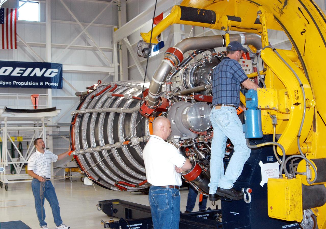 KENNEDY SPACE CENTER, FLA. - In the Space Shuttle Main Engine (SSME) Processing Facility, Boeing-Rocketdyne quality inspector Nick Grimm (center) monitors the work of technicians on his team as they lower SSME 2058, the first SSME fully assembled at KSC, onto an engine stand. The engine is being placed into a horizontal position in preparation for shipment to NASA’s Stennis Space Center in Mississippi to undergo a hot fire acceptance test. It is the first of five engines to be fully assembled on site to reach the desired number of 15 engines ready for launch at any given time in the Space Shuttle program. A Space Shuttle has three reusable main engines. Each is 14 feet long, weighs about 7,800 pounds, is seven-and-a-half feet in diameter at the end of its nozzle, and generates almost 400,000 pounds of thrust. Historically, SSMEs were assembled in Canoga Park, Calif., with post-flight inspections performed at KSC.  Both functions were consolidated in February 2002. The Rocketdyne Propulsion and Power division of The Boeing Co. manufactures the engines for NASA.