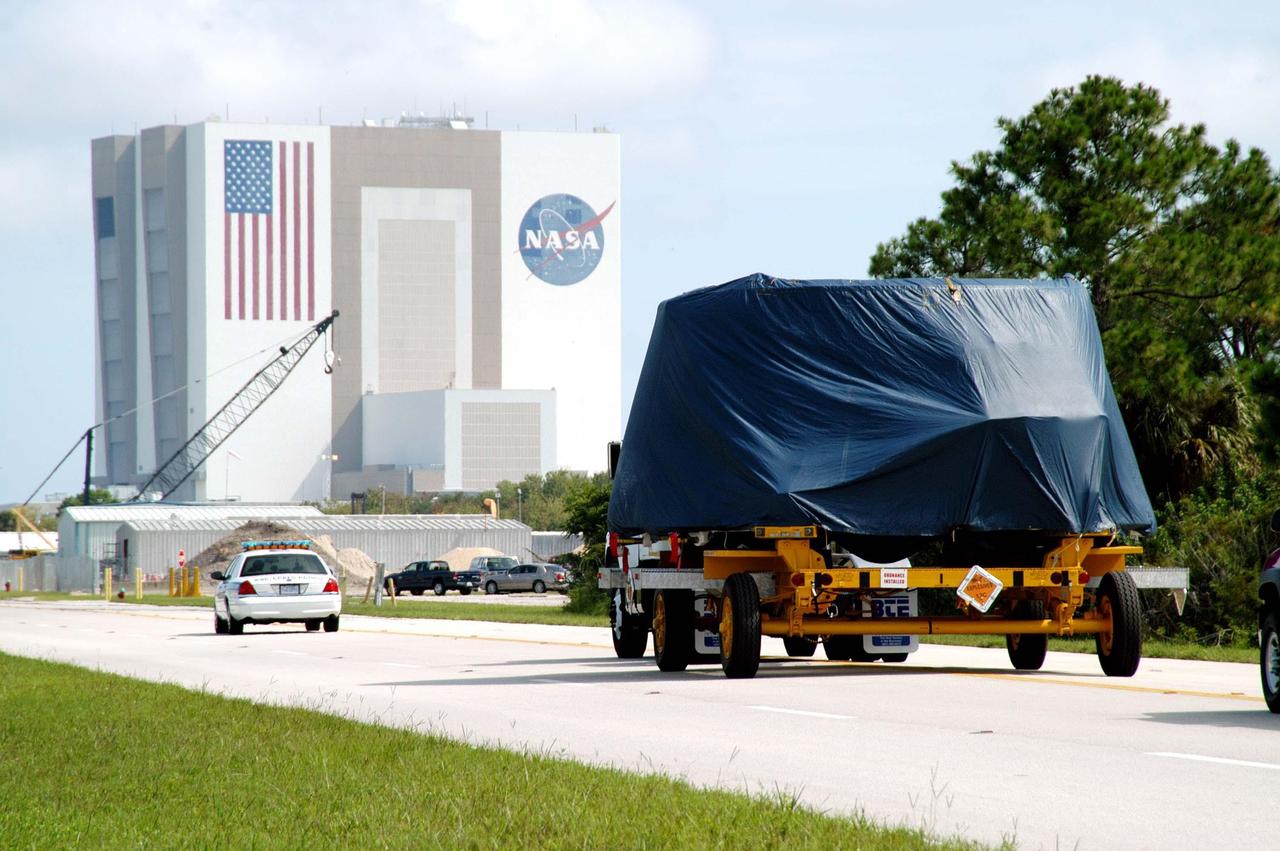 KENNEDY SPACE CENTER, FLA. - With Security escort, the first (left) solid rocket booster aft skirt for mission STS-114 nears the Vehicle Assembly Building (VAB) on its transfer to the Rotation Processing and Surge Facility (RPSF) for stacking.  At the RPSF an aft motor segment and an external tank attach ring will be installed.  The stack will then be moved to the Vehicle Assembly Building for further build-up.  This is the first transfer of a large piece of hardware from SRB to Ground Operations.  It is a significant milestone in the march to Return to Flight.