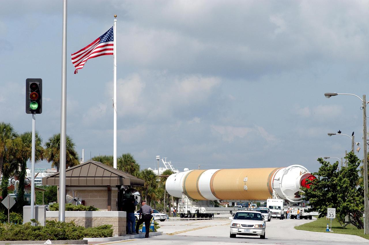 KENNEDY SPACE CENTER, FLA. - A Boeing Delta IV first stage spans the entire roadway as it approaches a Security gate at Cape Canaveral Air Force Station.  Two rockets were shipped by barge to Port Canaveral and offloaded onto an Elevating Platform Transporter for the journey to the Horizontal Integration Facility at Launch Complex 37, CCAFS. The rocket will be used for the December launching of the GOES-N weather satellite for NASA and NOAA. The GOES-N is the first in a series of three advanced weather satellites including GOES-O and GOES-P. This satellite will provide continuous monitoring necessary for intensive data analysis. It will provide a constant vigil for the atmospheric “triggers” of severe weather conditions such as tornadoes, flash floods, hail storms and hurricanes. When these conditions develop, GOES-N will be able to monitor storm development and track their movements.