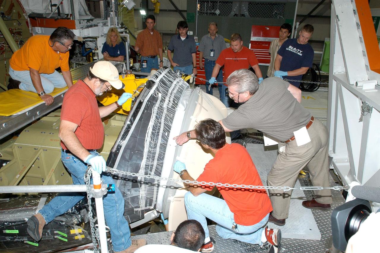 KENNEDY SPACE CENTER, FLA. - In the Orbiter Processing Facility, workers check the fit of the nose cap (right) after installation on the orbiter Atlantis.  The nose cap was removed from the vehicle in May and sent back to the vendor for thorough Non-Destructive Engineering evaluation and recoating.  Thermography was also performed to check for internal flaws.  This procedure uses high intensity light to heat areas that are immediately scanned with an infrared camera.  White Thermal Protection System blankets were reinstalled on the nose cap before installation.  Processing continues on Atlantis for its future mission to the International Space Station.