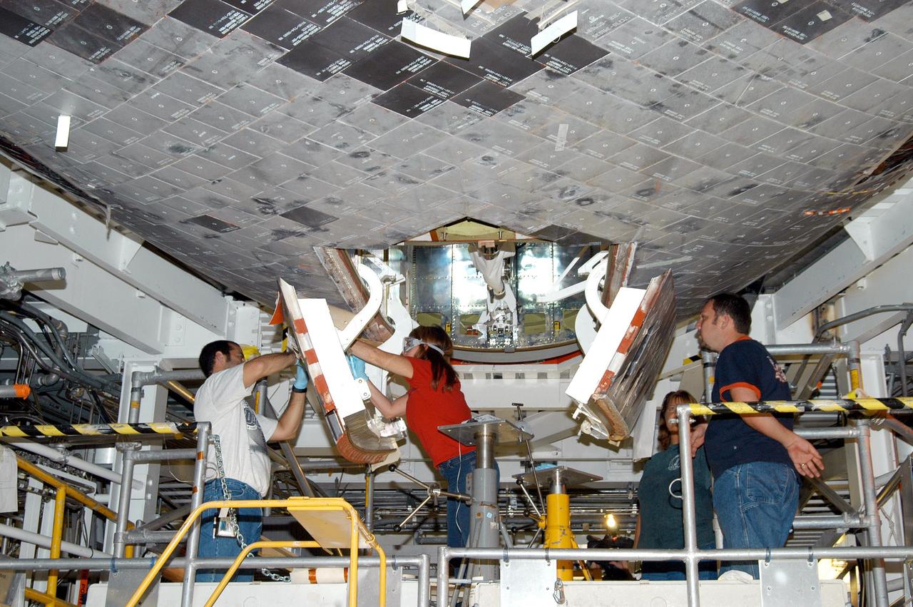 KENNEDY SPACE CENTER, FLA. -  Workers in the Orbiter Processing Facility prepare to close the nose wheel doors on Atlantis in preparation for the expected impact of Hurricane Frances on Saturday. Preparations at KSC include powering down the Space Shuttle orbiters, closing their payload bay doors and stowing their landing gear. They are also taking precautions against flooding by moving spacecraft hardware off the ground and sandbagging facilities. The Orbiter Processing Facility is constructed of concrete and steel and was designed to withstand winds of 105 mph.  The Vehicle Assembly Building is constructed of concrete and steel and was designed to withstand winds of 125 mph. Other payload and flight hardware support facilities can endure winds of 110 mph.  Launch pads and the Payload Hazardous Servicing Facility can withstand 125-mph winds.