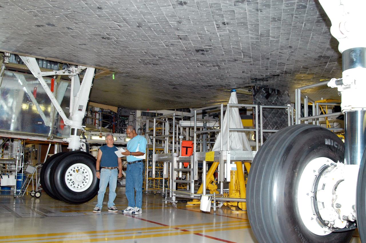 KENNEDY SPACE CENTER, FLA. -  Workers in the Orbiter Processing Facility prepare to stow the landing gear on the orbiter Atlantis in preparation for the expected impact of Hurricane Frances on Saturday. Other preparations at KSC include powering down the Space Shuttle orbiters, and closing their payload bay doors. Workers are also taking precautions against flooding by moving spacecraft hardware off the ground and sandbagging facilities. The Orbiter Processing Facility is constructed of concrete and steel and was designed to withstand winds of 105 mph.  The Vehicle Assembly Building is constructed of concrete and steel and was designed to withstand winds of 125 mph. Other payload and flight hardware support facilities can endure winds of 110 mph.  Launch pads and the Payload Hazardous Servicing Facility can withstand 125-mph winds.