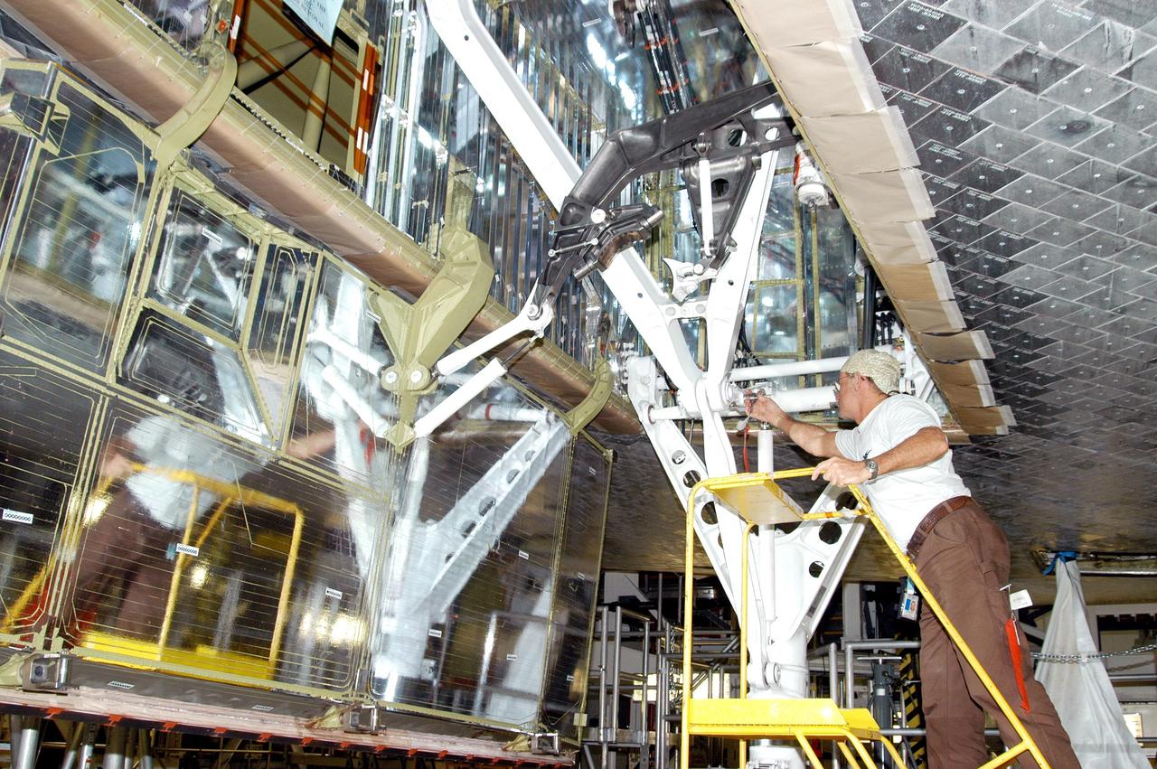 KENNEDY SPACE CENTER, FLA. -  Workers in the Orbiter Processing Facility prepare the wheel bay to stow Atlantis’ landing gear in preparation for the expected impact of Hurricane Frances on Saturday. Other preparations at KSC include powering down the Space Shuttle orbiters, and closing their payload bay doors. Workers are also taking precautions against flooding by moving spacecraft hardware off the ground and sandbagging facilities. The Orbiter Processing Facility is constructed of concrete and steel and was designed to withstand winds of 105 mph.  The Vehicle Assembly Building is constructed of concrete and steel and was designed to withstand winds of 125 mph. Other payload and flight hardware support facilities can endure winds of 110 mph.  Launch pads and the Payload Hazardous Servicing Facility can withstand 125-mph winds.