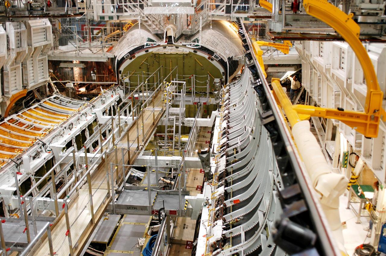 KENNEDY SPACE CENTER, FLA. -  In the Orbiter Processing Facility, workers prepare to close the payload bay doors on Atlantis in preparation for the expected impact of Hurricane Frances on Saturday. Other preparations at KSC include powering down the Space Shuttle orbiters and stowing the landing gear.  Workers are also taking precautions against flooding by moving spacecraft hardware off the ground and sandbagging facilities. The Orbiter Processing Facility is constructed of concrete and steel and was designed to withstand winds of 105 mph.  The Vehicle Assembly Building is constructed of concrete and steel and was designed to withstand winds of 125 mph. Other payload and flight hardware support facilities can endure winds of 110 mph.  Launch pads and the Payload Hazardous Servicing Facility can withstand 125-mph winds.